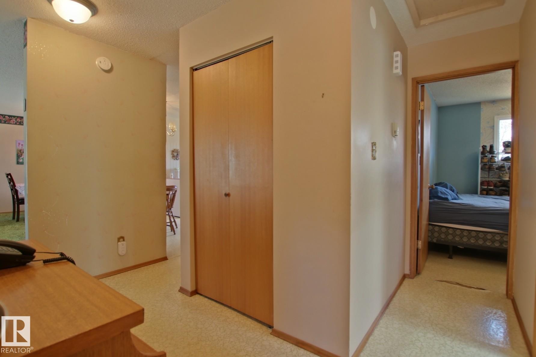 Hallway featuring wood-finish bi-fold closet doors, light-colored walls, and textured ceiling - 3539 104 Street, Edmonton, AB - Indoor Photo Showing Other Room