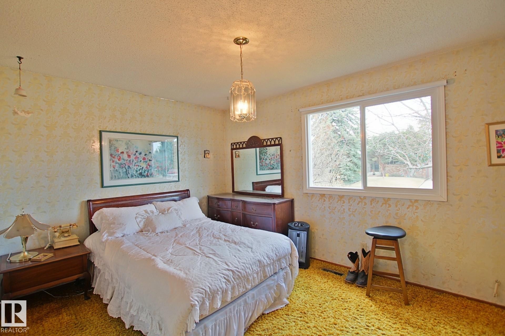 Room featuring a bright window, textured wall finish, and a central pendant light fixture - 3539 104 Street, Edmonton, AB - Indoor Photo Showing Bedroom