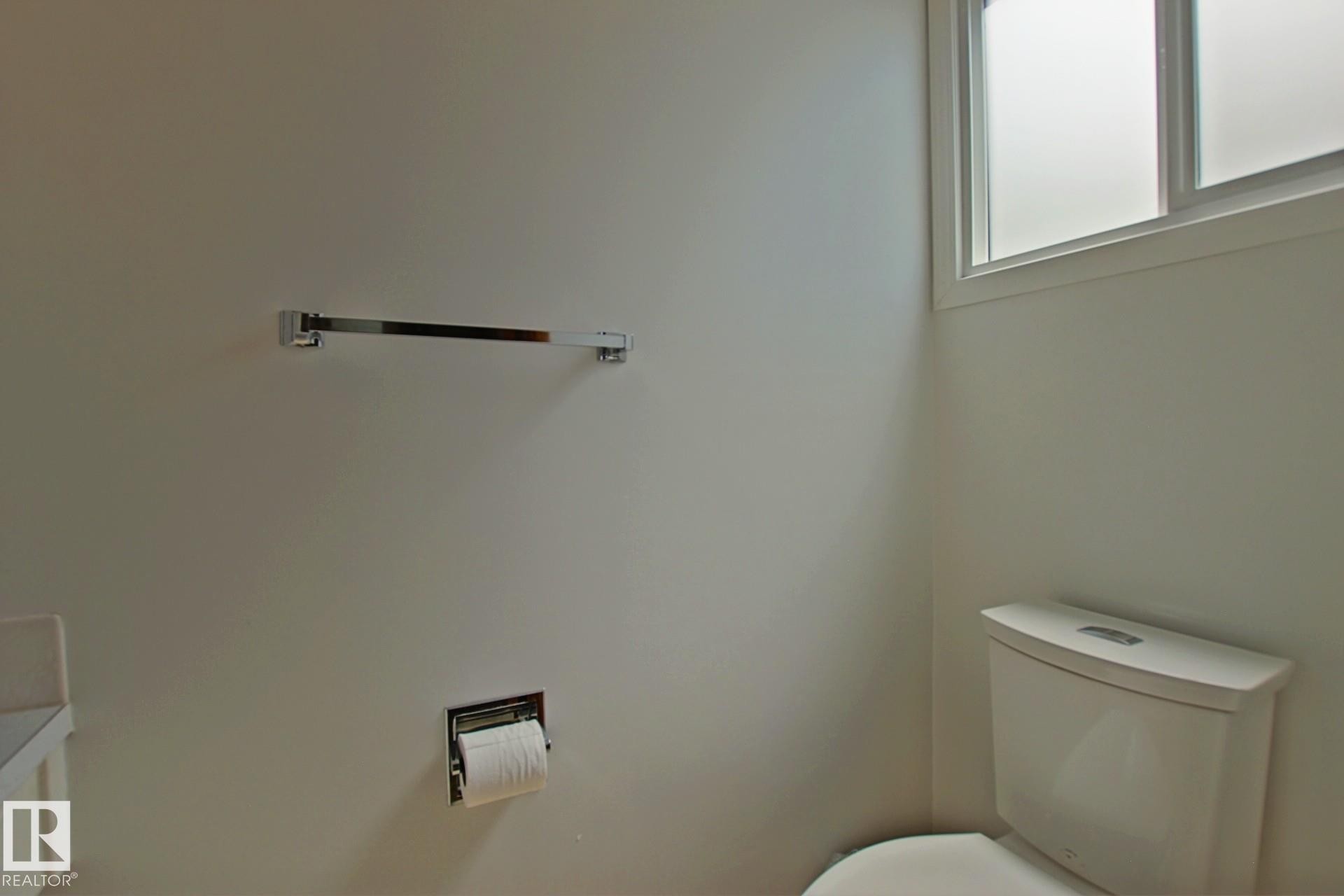 Bathroom featuring a white toilet, chrome towel bar, and a frosted window - 3539 104 Street, Edmonton, AB - Indoor Photo Showing Bathroom