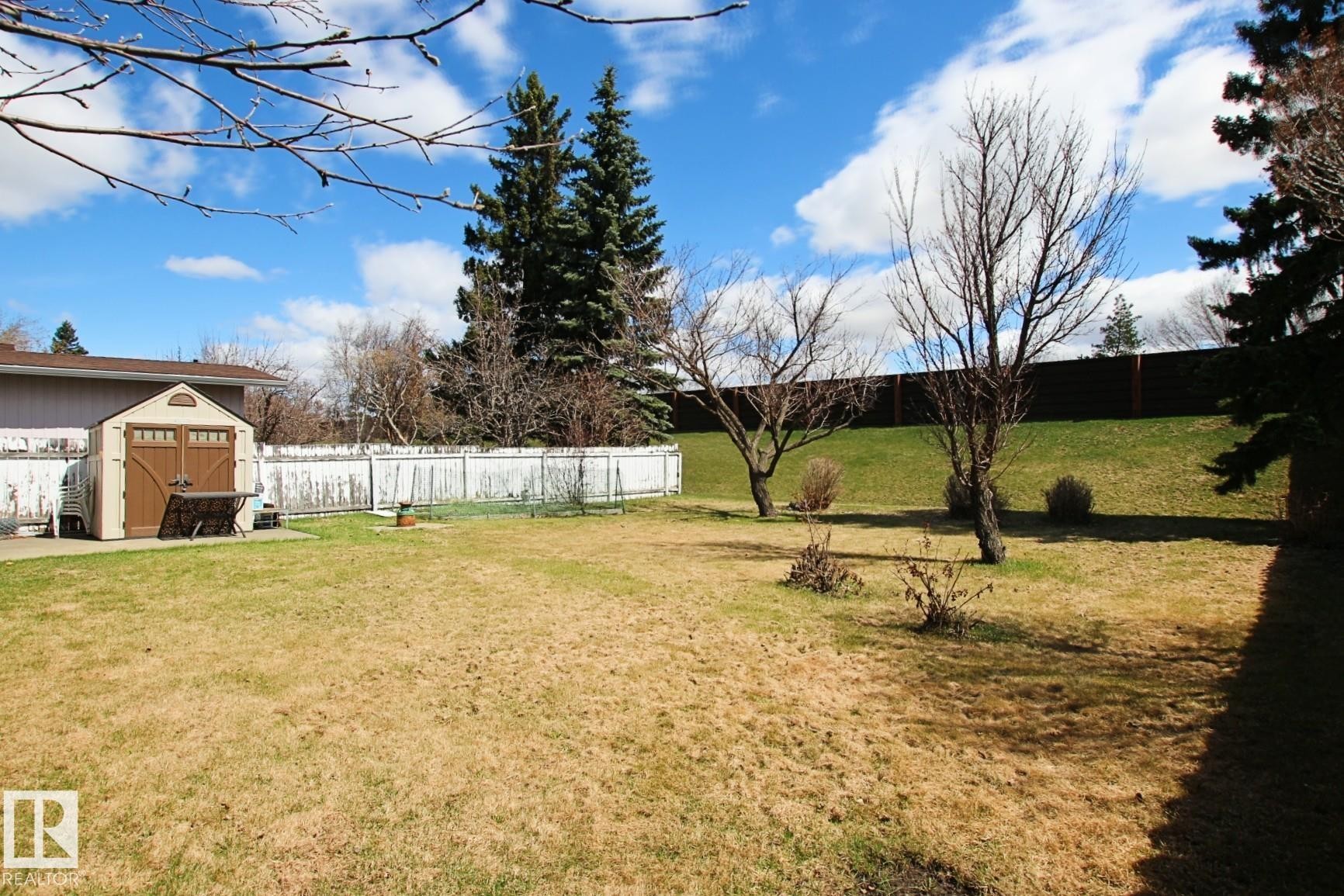 Expansive backyard featuring a built-in storage shed, mature trees, and a wooden privacy fence - 3539 104 Street, Edmonton, AB - Outdoor