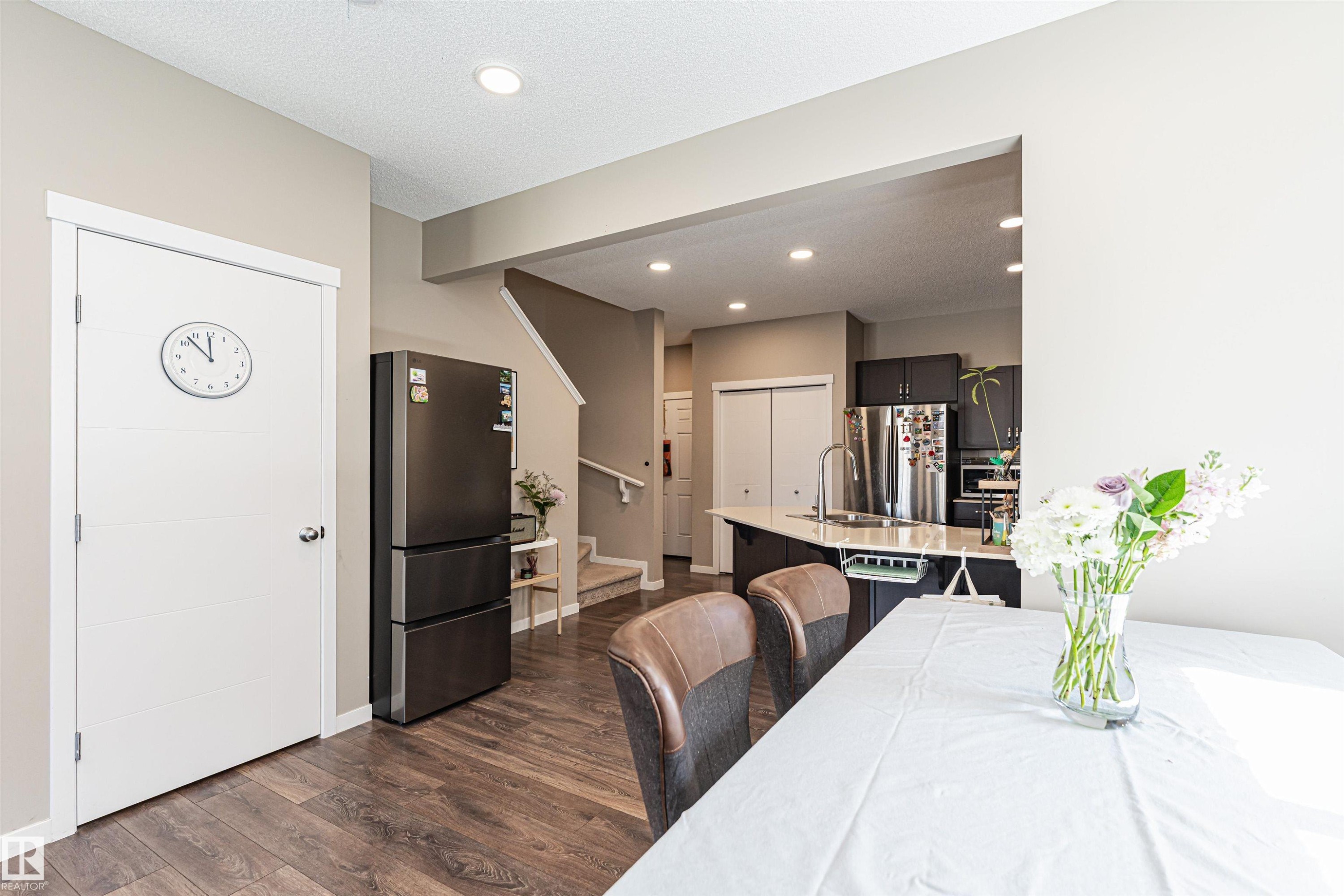 Open-concept kitchen and dining area featuring dark wood-finish flooring - 4452 Annett Common, Edmonton, AB
