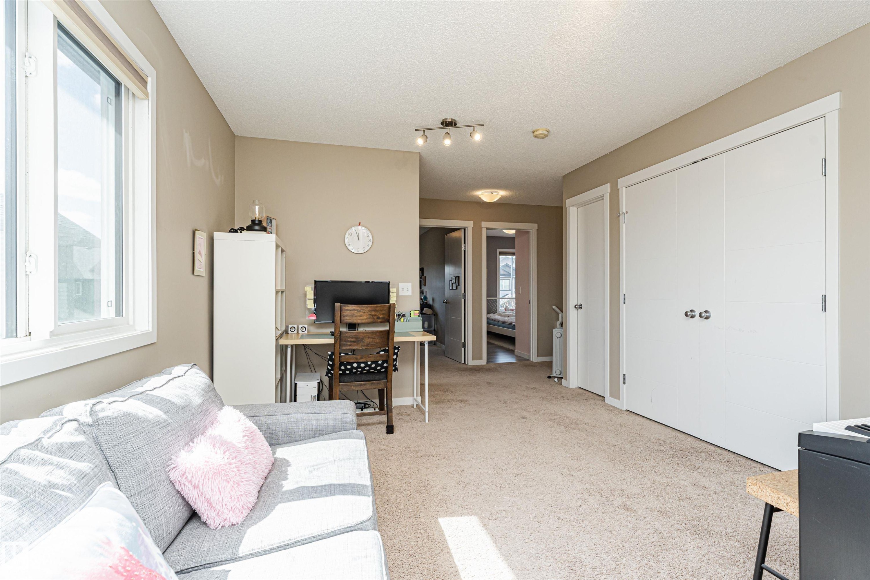 Carpeted room featuring a large window with white trim, track lighting, and a double-door closet with chrome hardware - 4452 Annett Common, Edmonton, AB