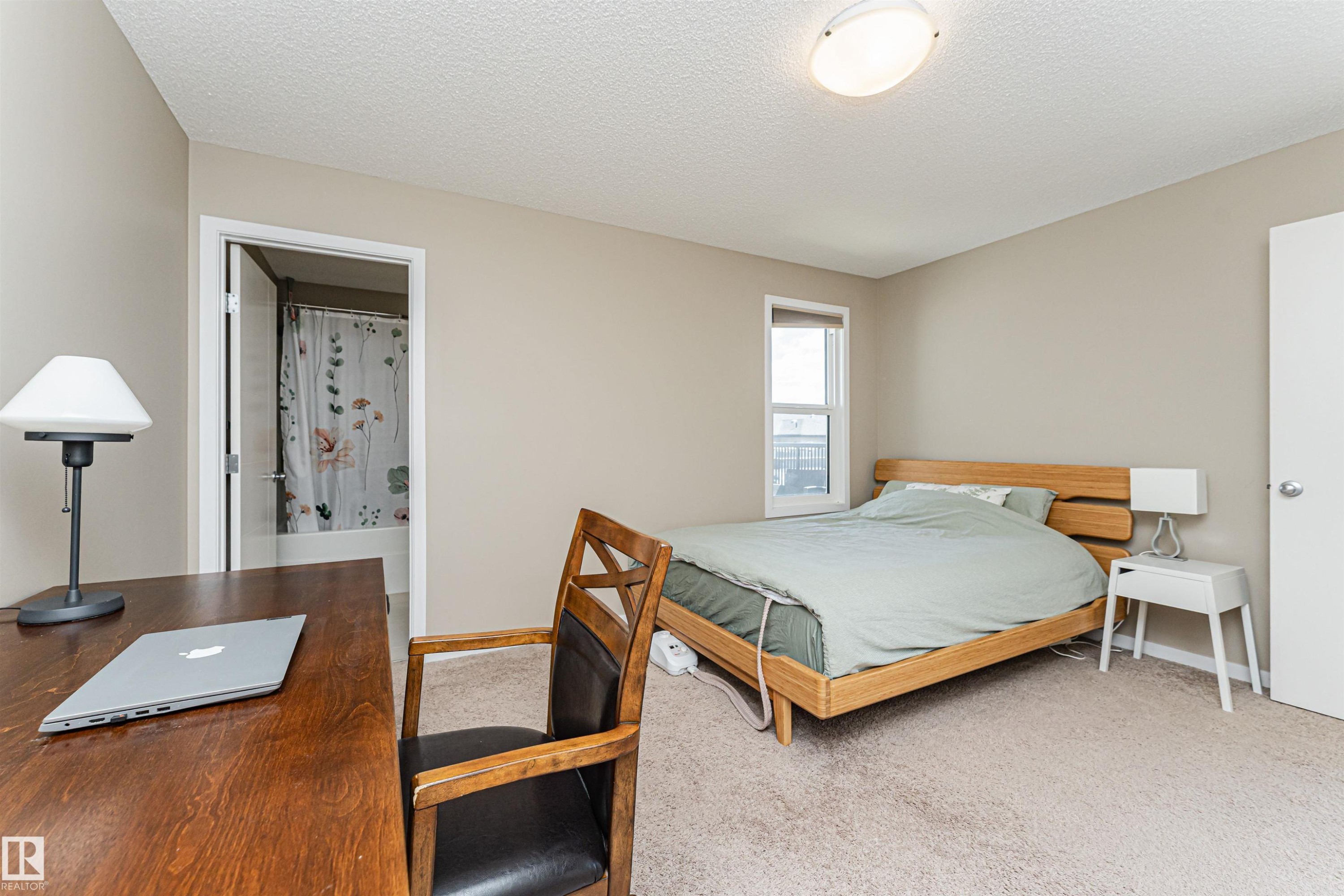 Bedroom featuring neutral wall tones, carpeted flooring, a flush-mount ceiling light fixture, and a window with a white frame - 4452 Annett Common, Edmonton, AB