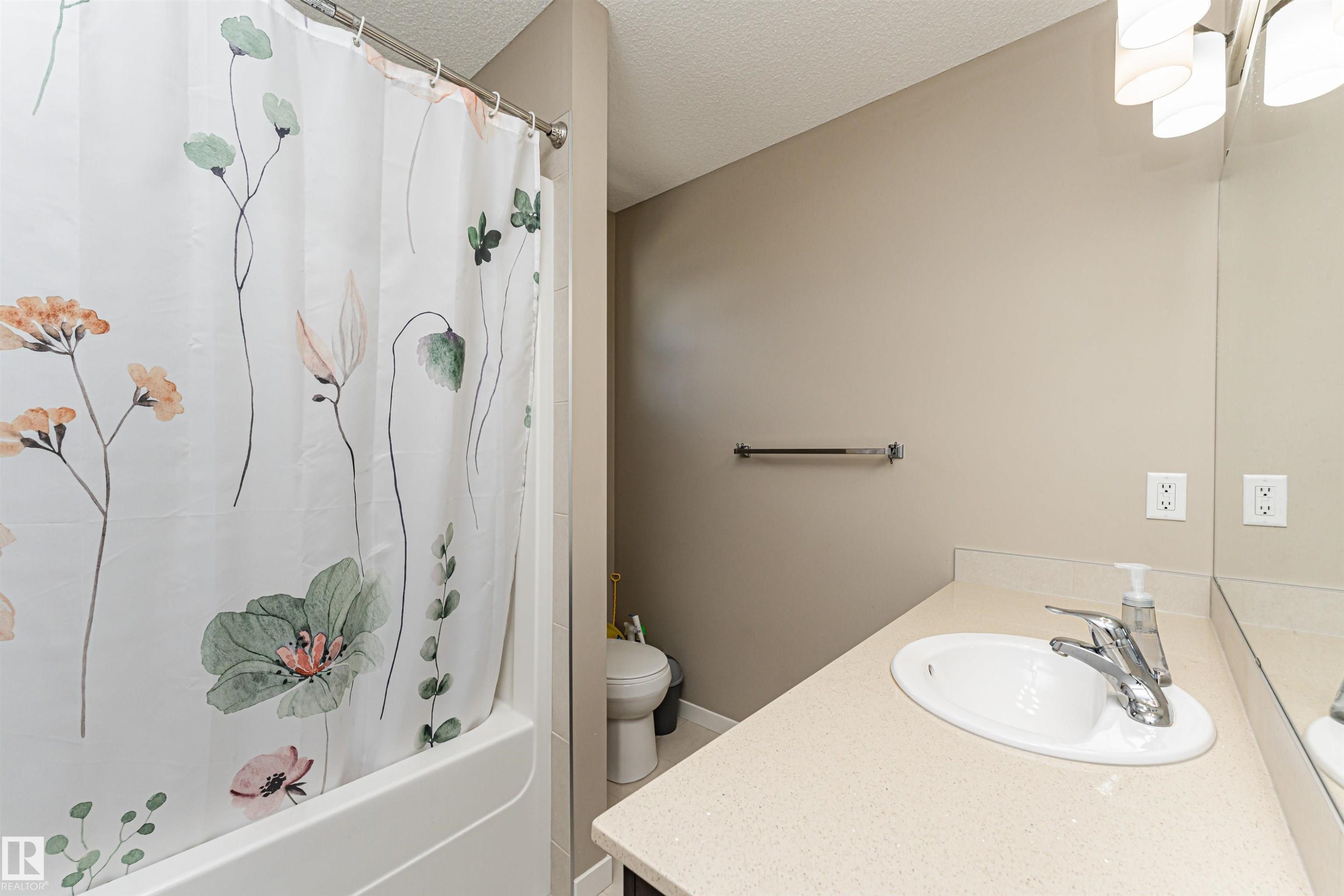 Bathroom featuring a shower-tub combination, single vanity with integrated sink, and vanity light fixture - 4452 Annett Common, Edmonton, AB