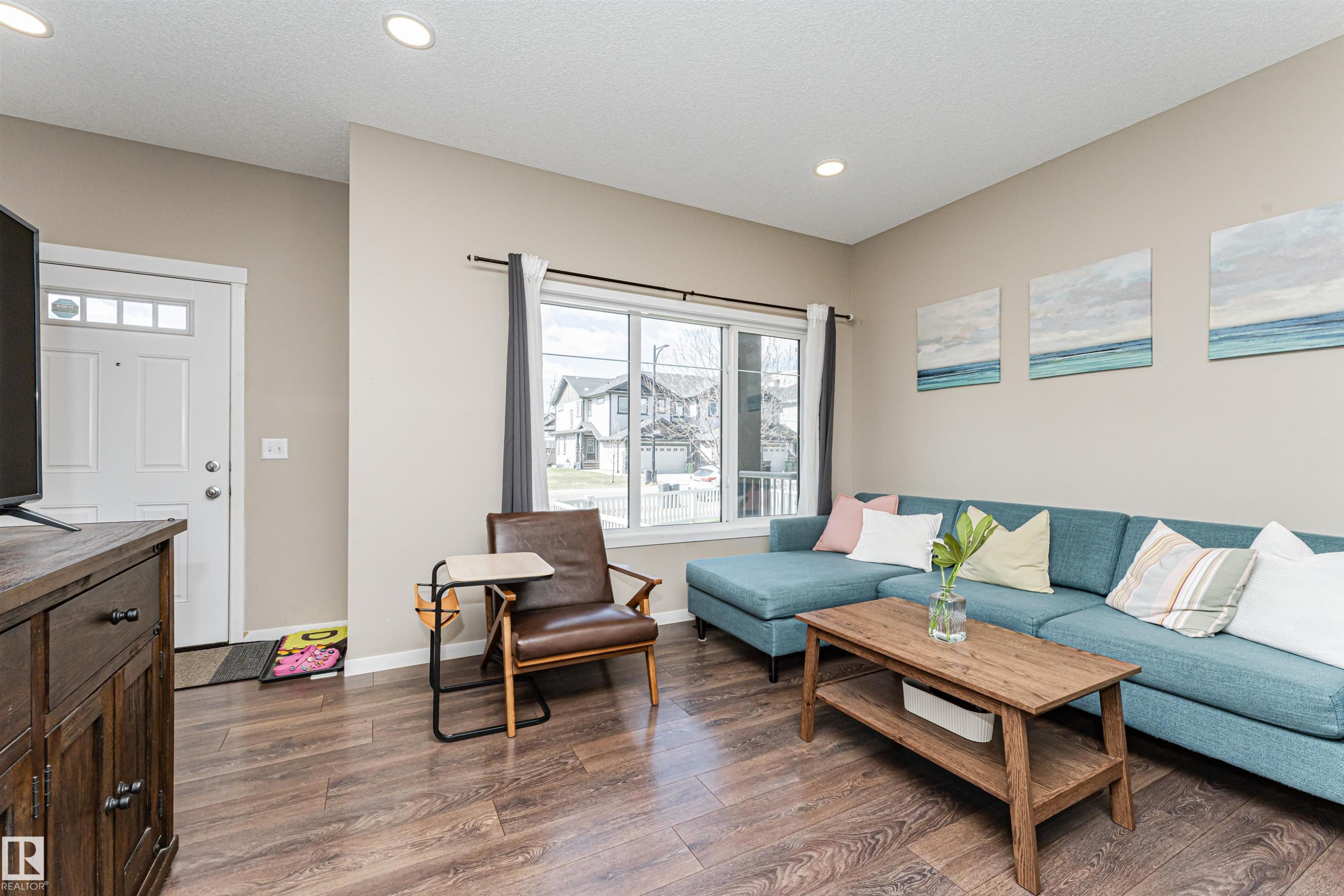 Open-concept living area with wood-finish flooring, neutral wall tones, and recessed lighting - 4452 Annett Common, Edmonton, AB