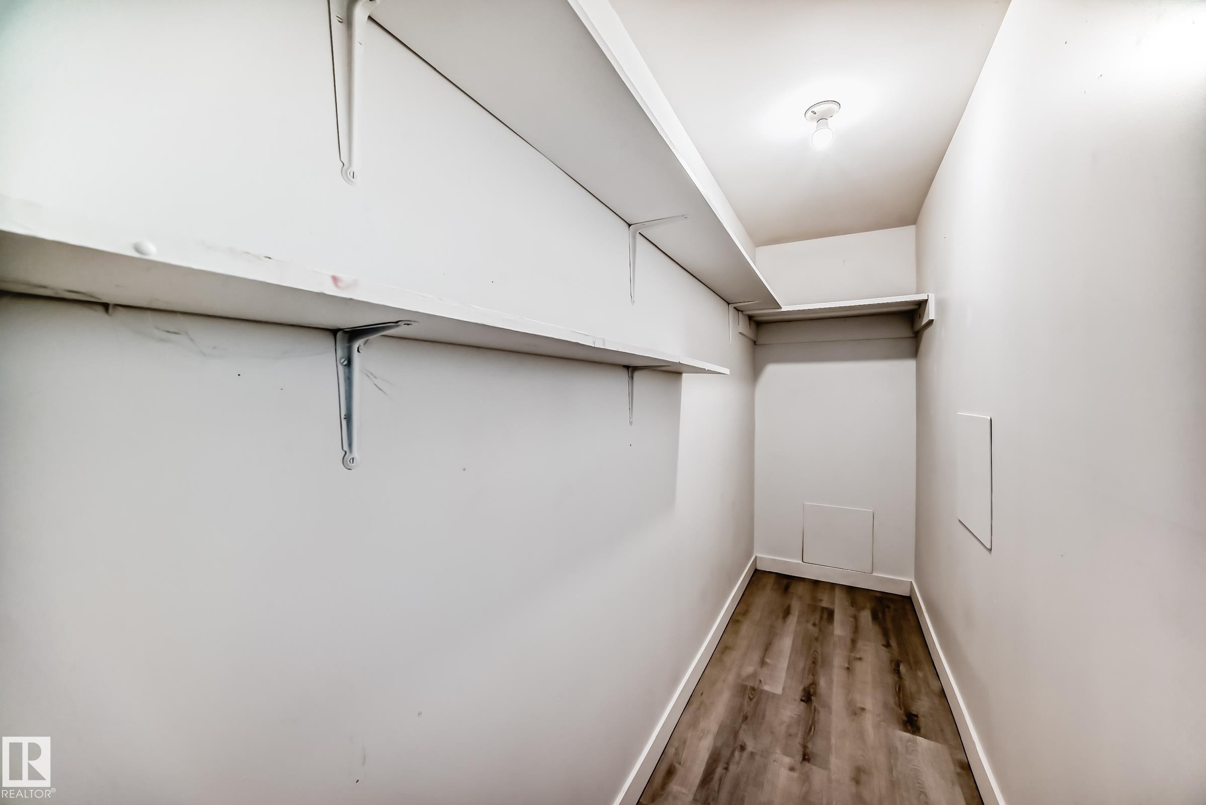 Walk-in closet featuring wood-finish flooring, white walls, and built-in shelving - 12825 102 Street, Edmonton, AB - Indoor Photo Showing Other Room