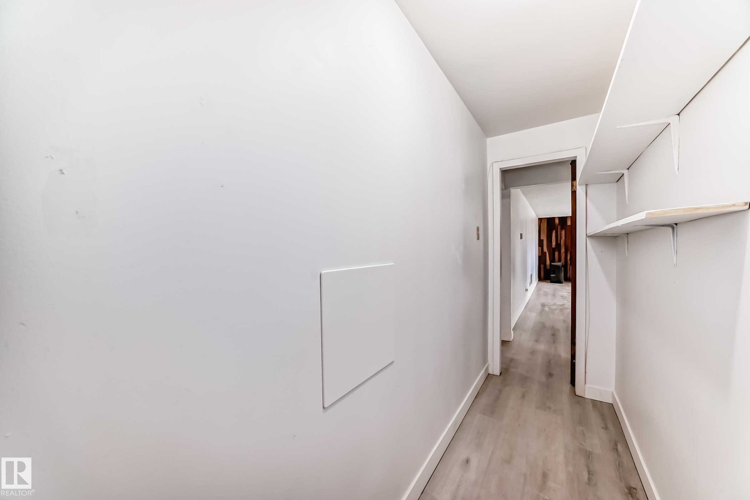 Hallway featuring light-toned wood-finish flooring, white walls, and built-in shelving - 12825 102 Street, Edmonton, AB - Indoor Photo Showing Other Room
