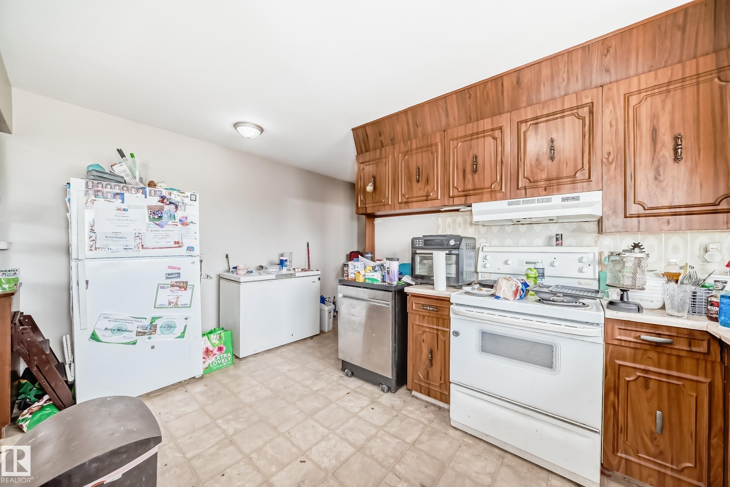 Kitchen featuring wood-panel cabinetry, white range, and tiled flooring - 12825 102 Street, Edmonton, AB - Indoor Photo Showing Kitchen