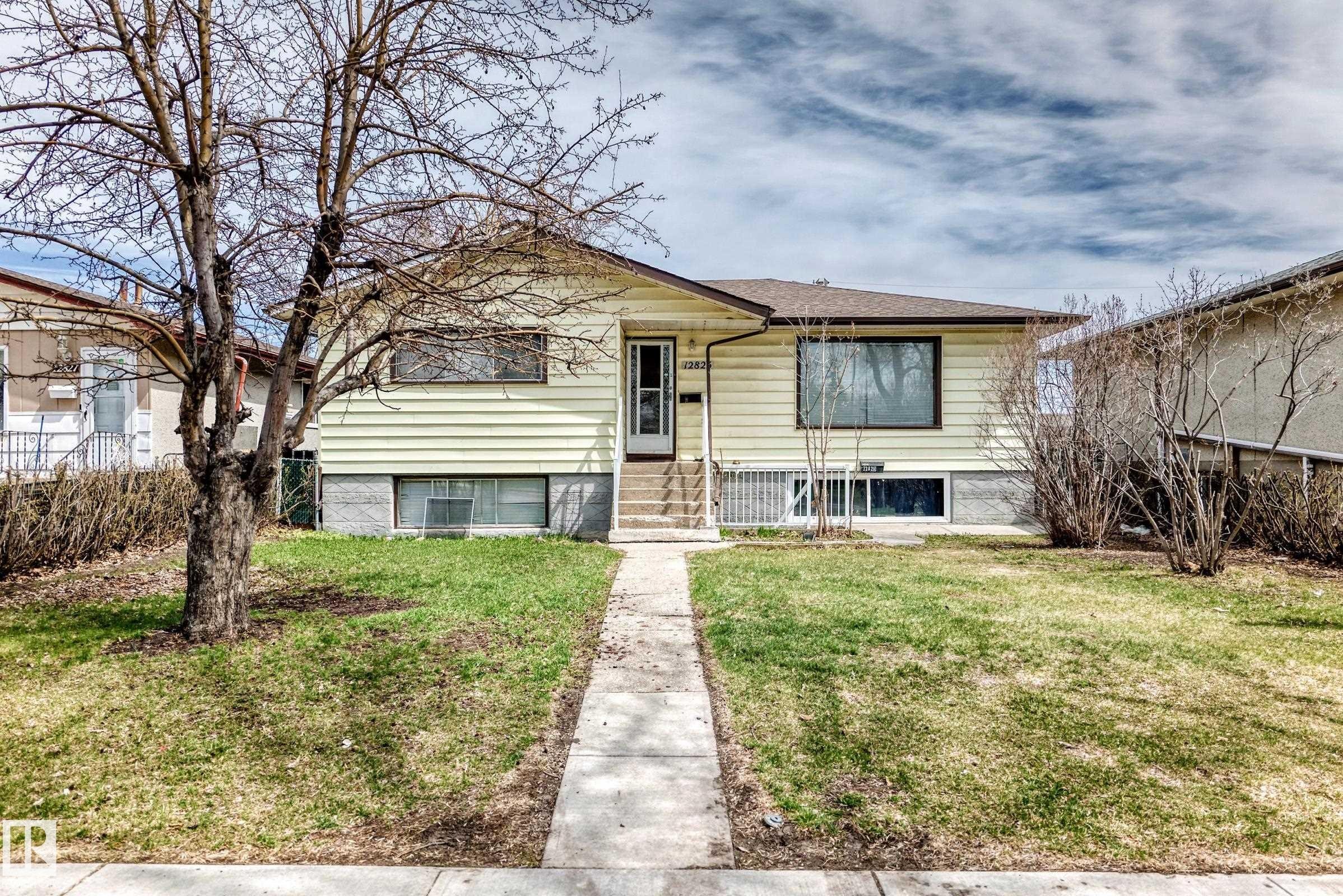 Bungalow residence featuring light yellow siding, a prominent front entrance with a white door, and a concrete pathway leading to the street - 12825 102 Street, Edmonton, AB - Outdoor