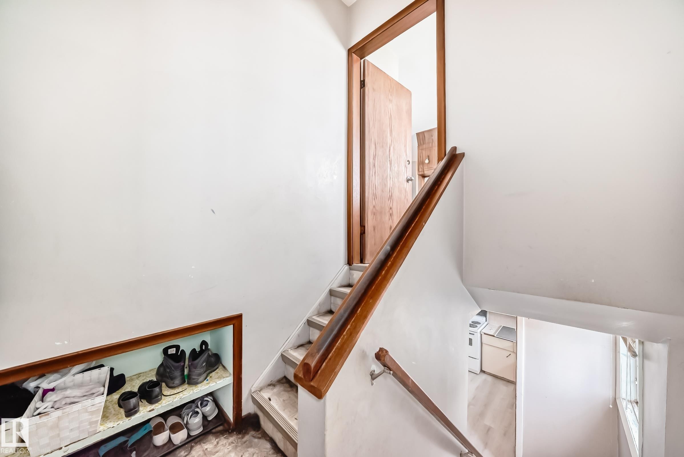 Stairwell featuring natural wood handrails, light-toned wall finishes, and an open doorway leading to an additional space - 12825 102 Street, Edmonton, AB - Indoor Photo Showing Other Room