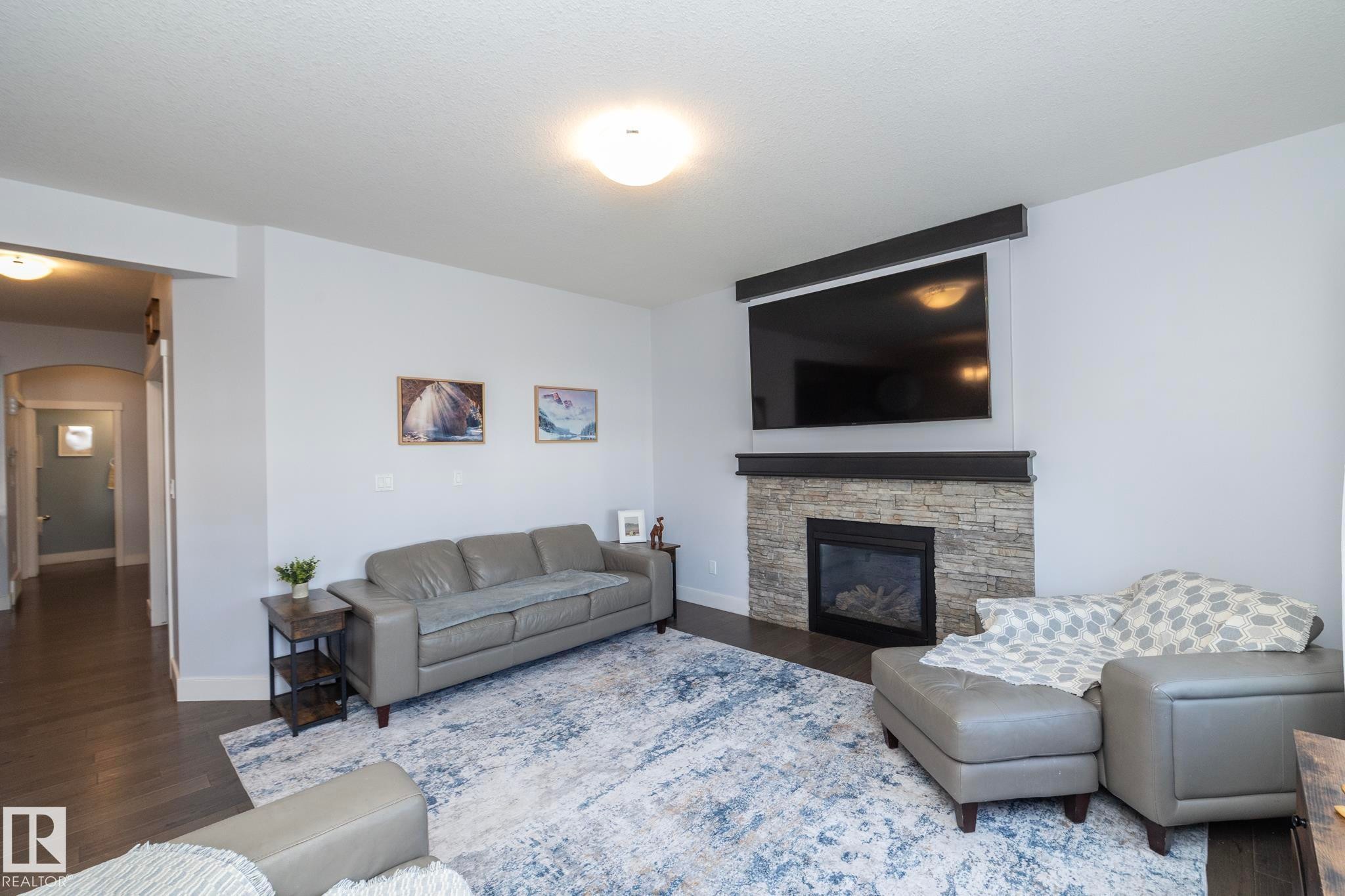 Living area featuring wood-finish flooring and light-toned walls - 2016 Redtail Common, Edmonton, AB - Indoor Photo Showing Living Room With Fireplace