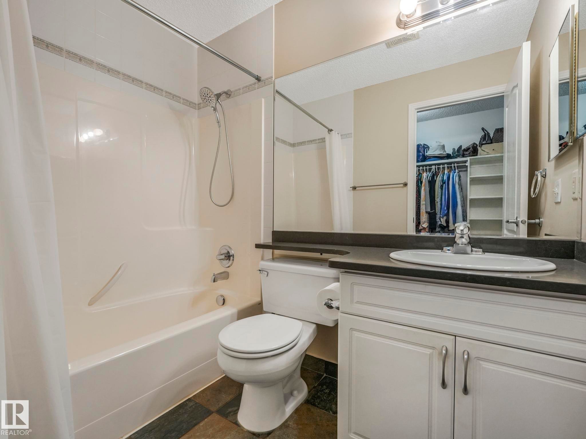 Bathroom featuring a white vanity with cabinet storage, an integrated sink, and a dark countertop - 317 2420 108 Street, Edmonton, AB - Indoor Photo Showing Bathroom