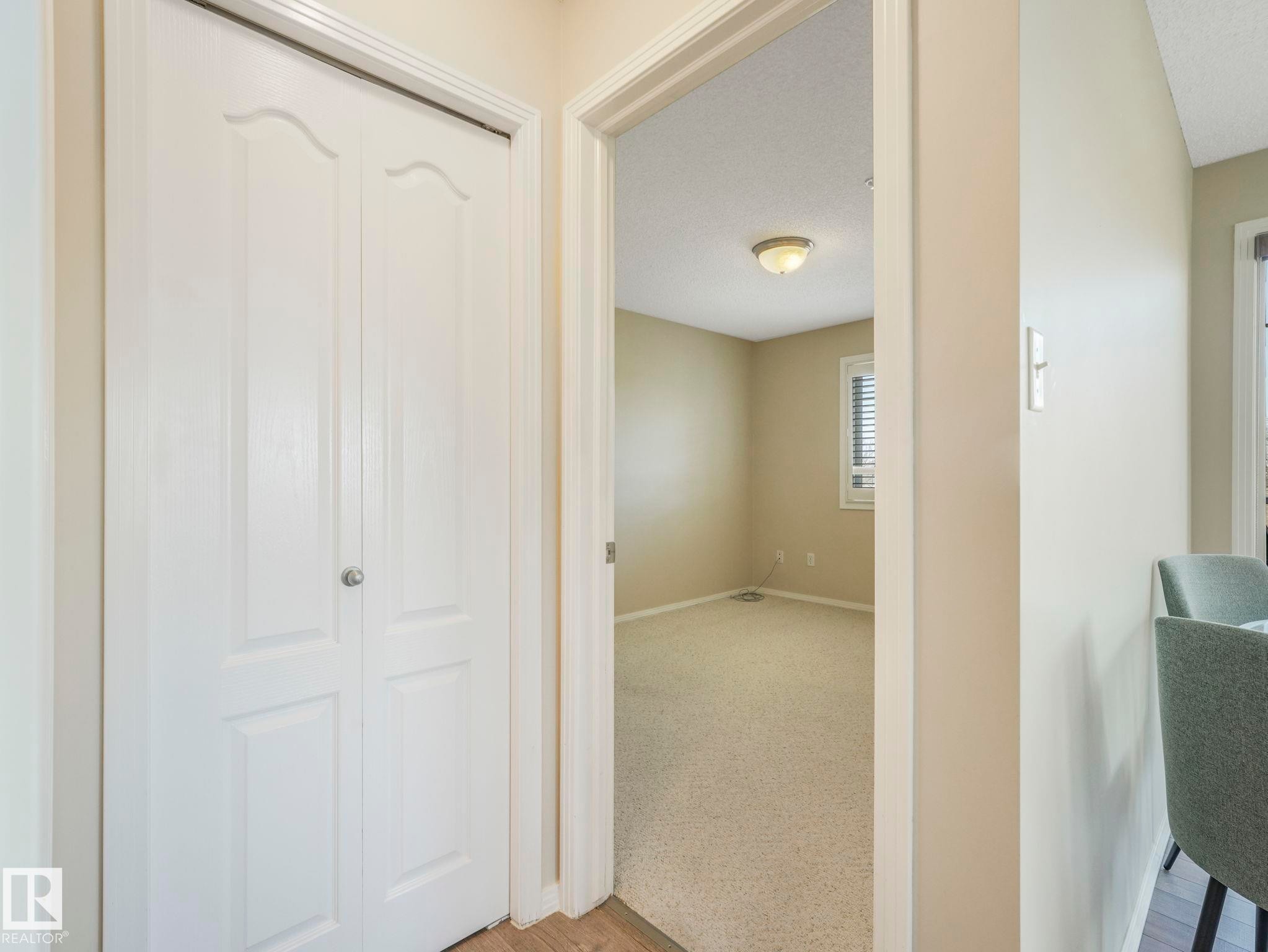 White bi-fold closet doors with panel detailing - 317 2420 108 Street, Edmonton, AB - Indoor Photo Showing Other Room