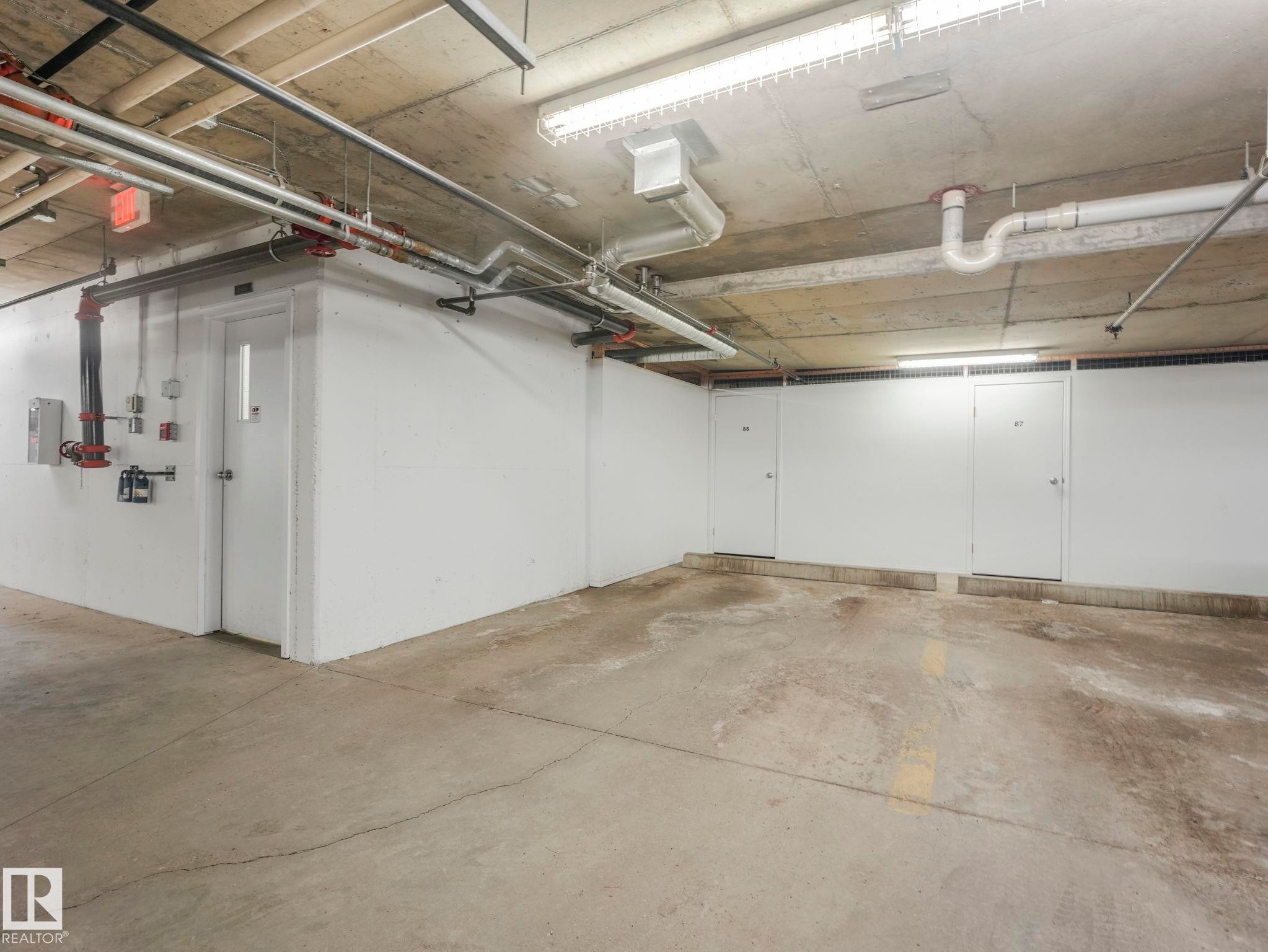 Concrete flooring with visible utility piping and fluorescent lighting - 317 2420 108 Street, Edmonton, AB - Indoor Photo Showing Garage