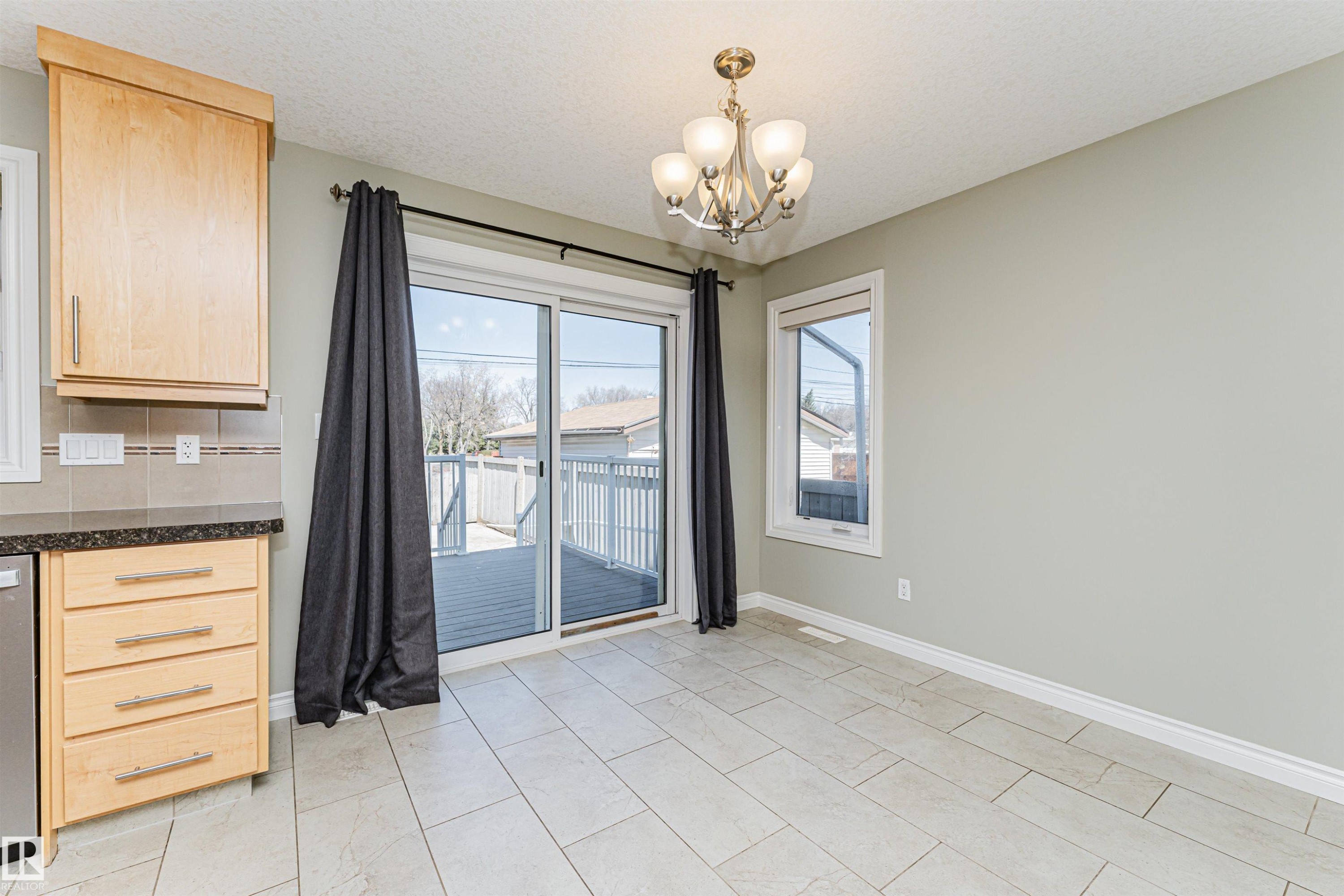 Sliding glass doors opening to a wood-finish deck - 8530 76 Avenue, Edmonton, AB - Indoor