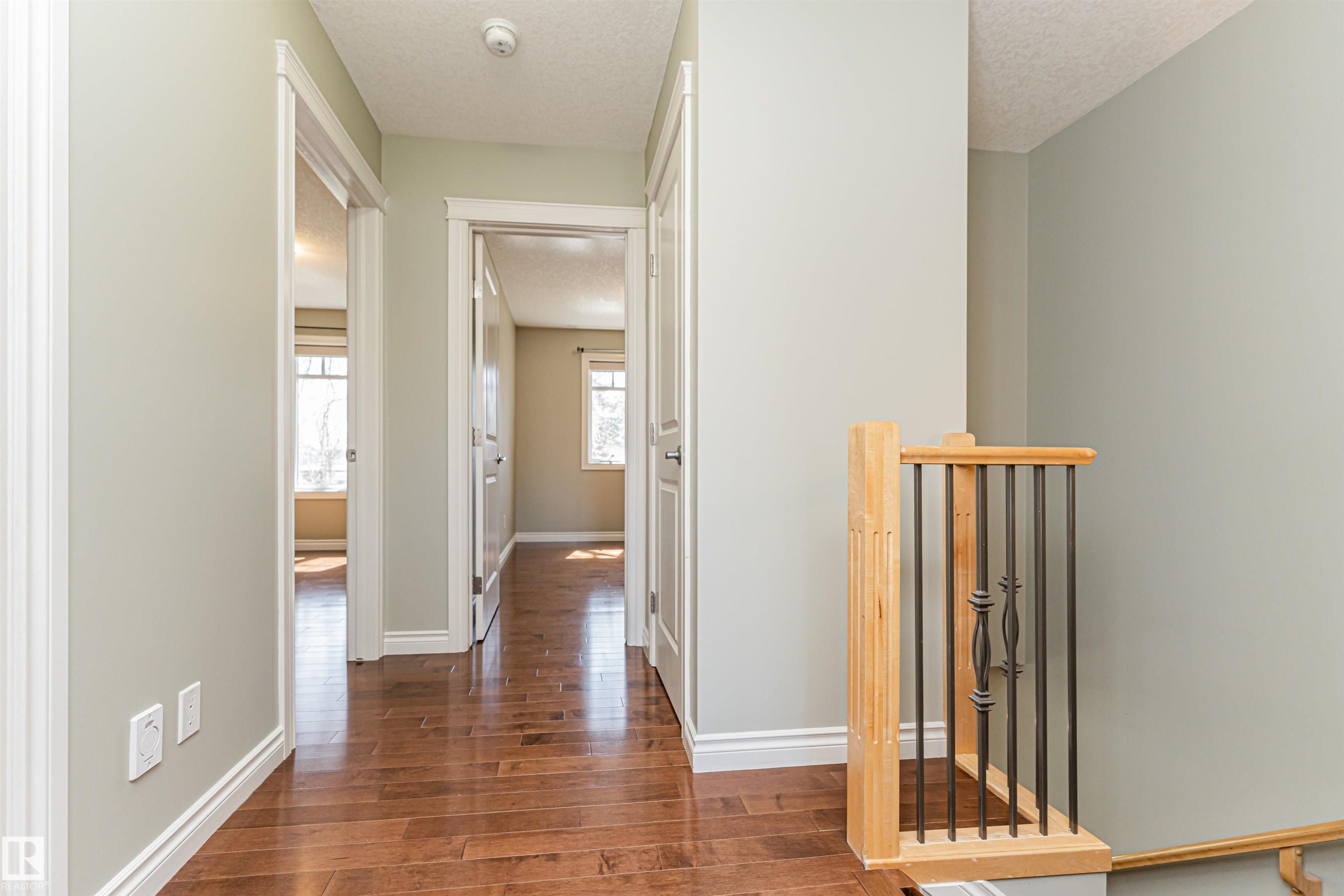 Hallway featuring wood-finish flooring, light neutral wall paint, and white trim - 8530 76 Avenue, Edmonton, AB - Indoor Photo Showing Other Room