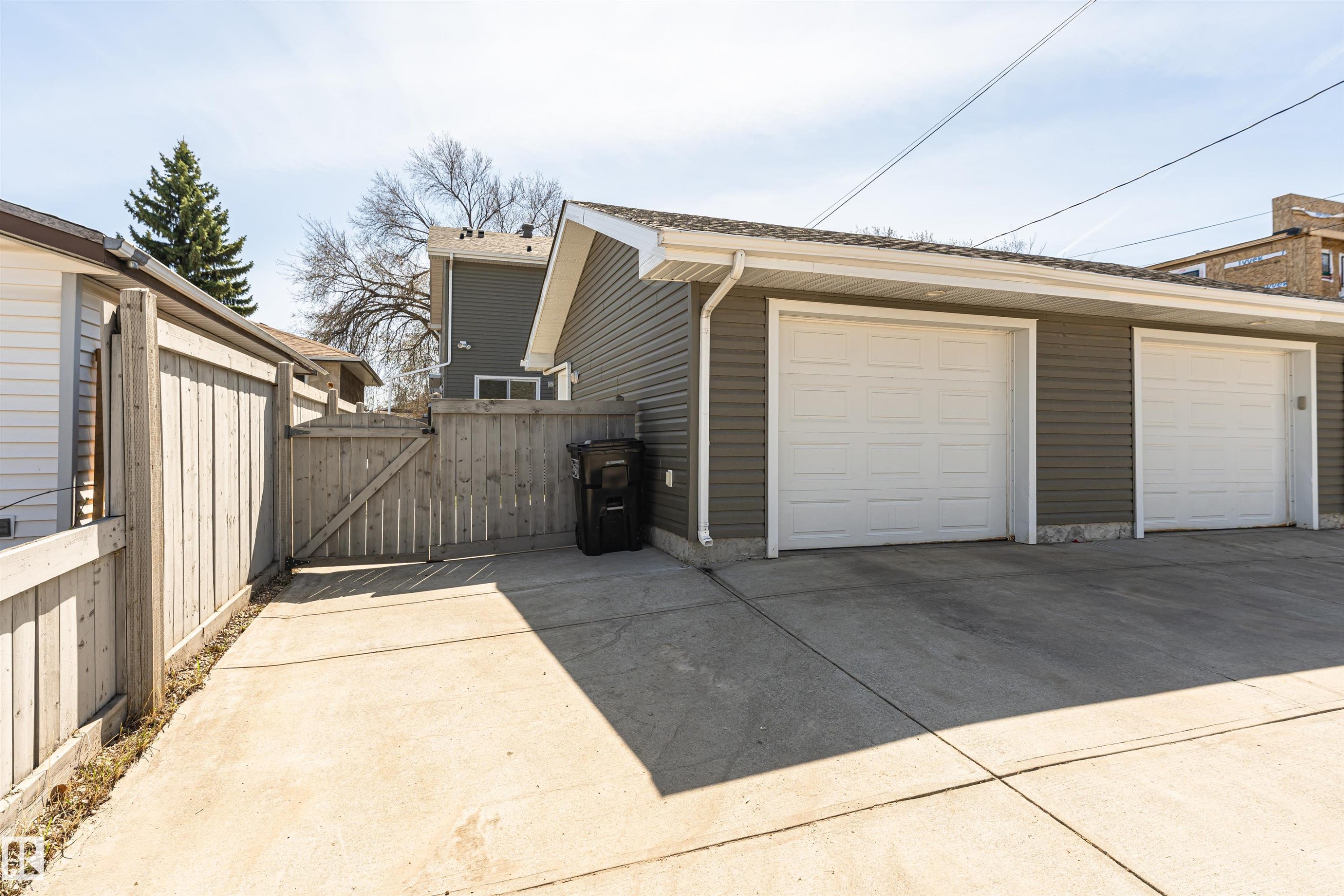 Detached garage with two white overhead doors and gray horizontal siding - 8530 76 Avenue, Edmonton, AB - Outdoor With Exterior