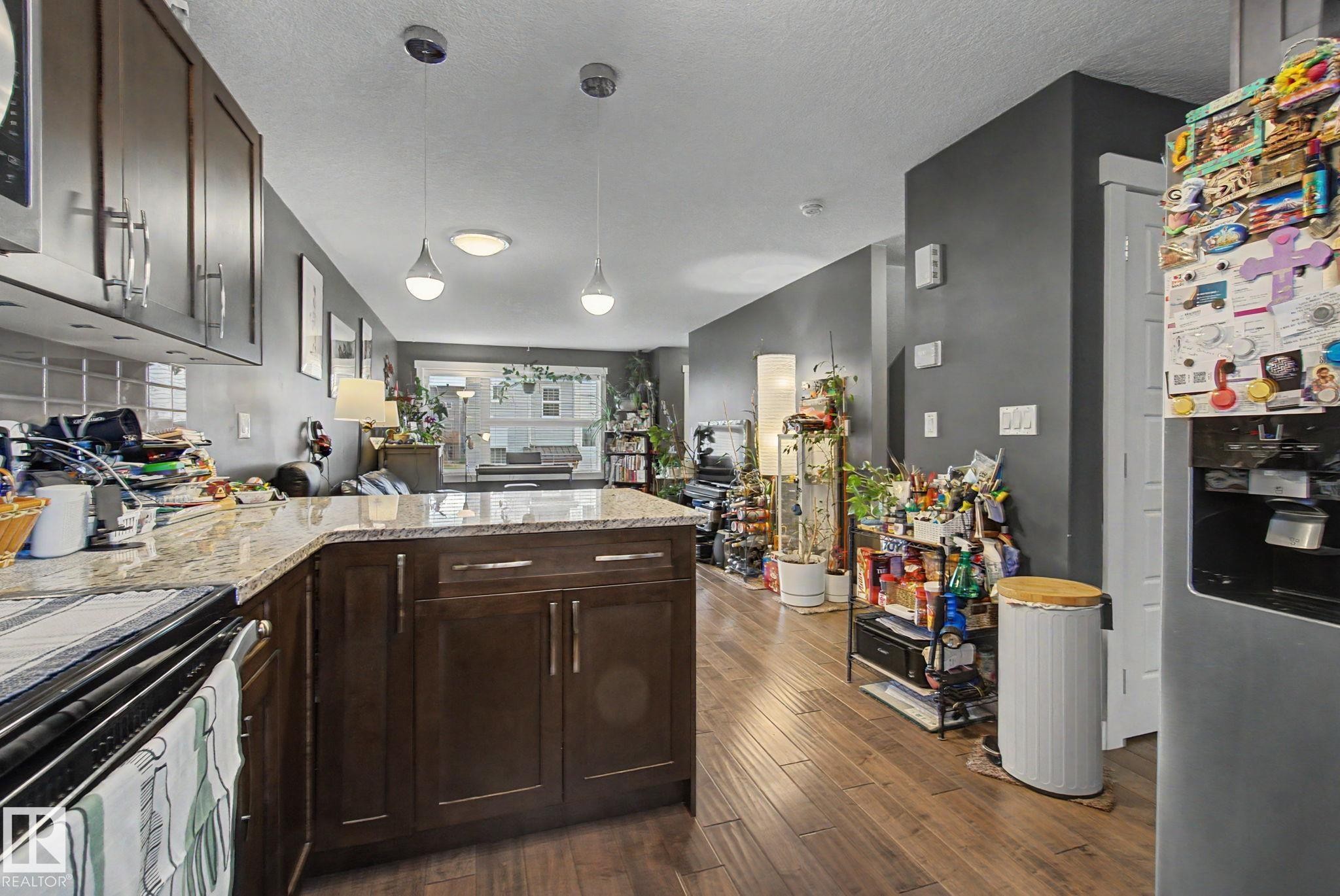 Kitchen featuring wood-finish cabinetry, light-toned countertops, and a tiled backsplash - 210 401 Southfork Drive, Leduc, AB - Indoor Photo Showing Kitchen