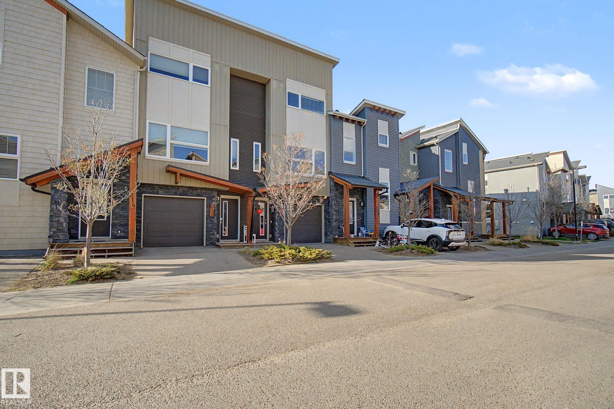 Modern exterior featuring mixed-material siding, a single-car garage, and multiple large windows - 210 401 Southfork Drive, Leduc, AB - Outdoor