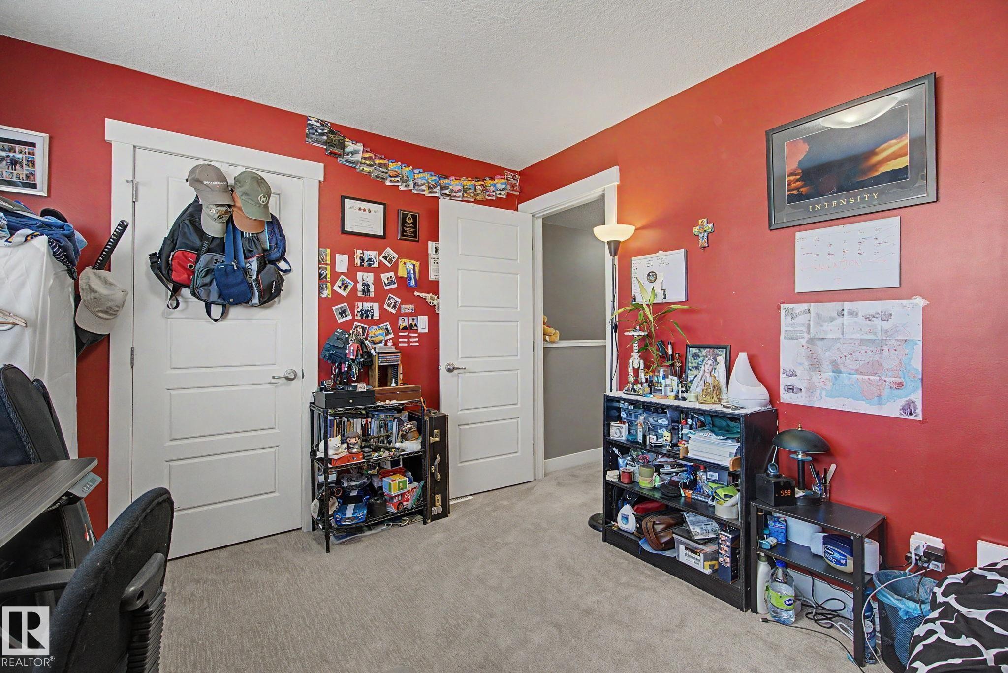 Room featuring textured carpeting, red painted walls, white trim, and multiple paneled doors with silver hardware - 210 401 Southfork Drive, Leduc, AB - Indoor Photo Showing Other Room