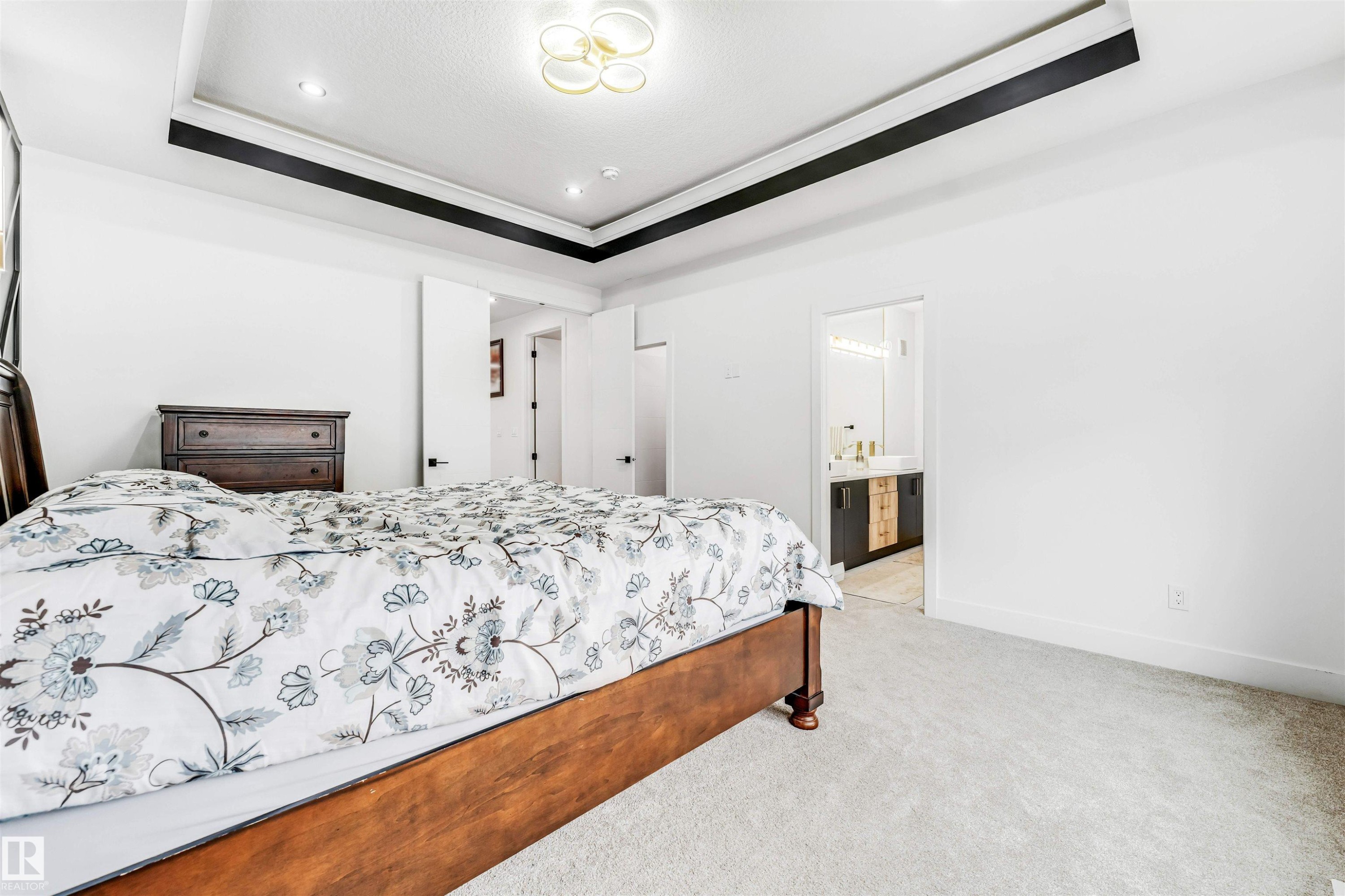 Recessed lighting and a decorative ceiling fixture illuminate the tray ceiling with contrasting trim - 1827 17 Avenue, Edmonton, AB - Indoor Photo Showing Bedroom