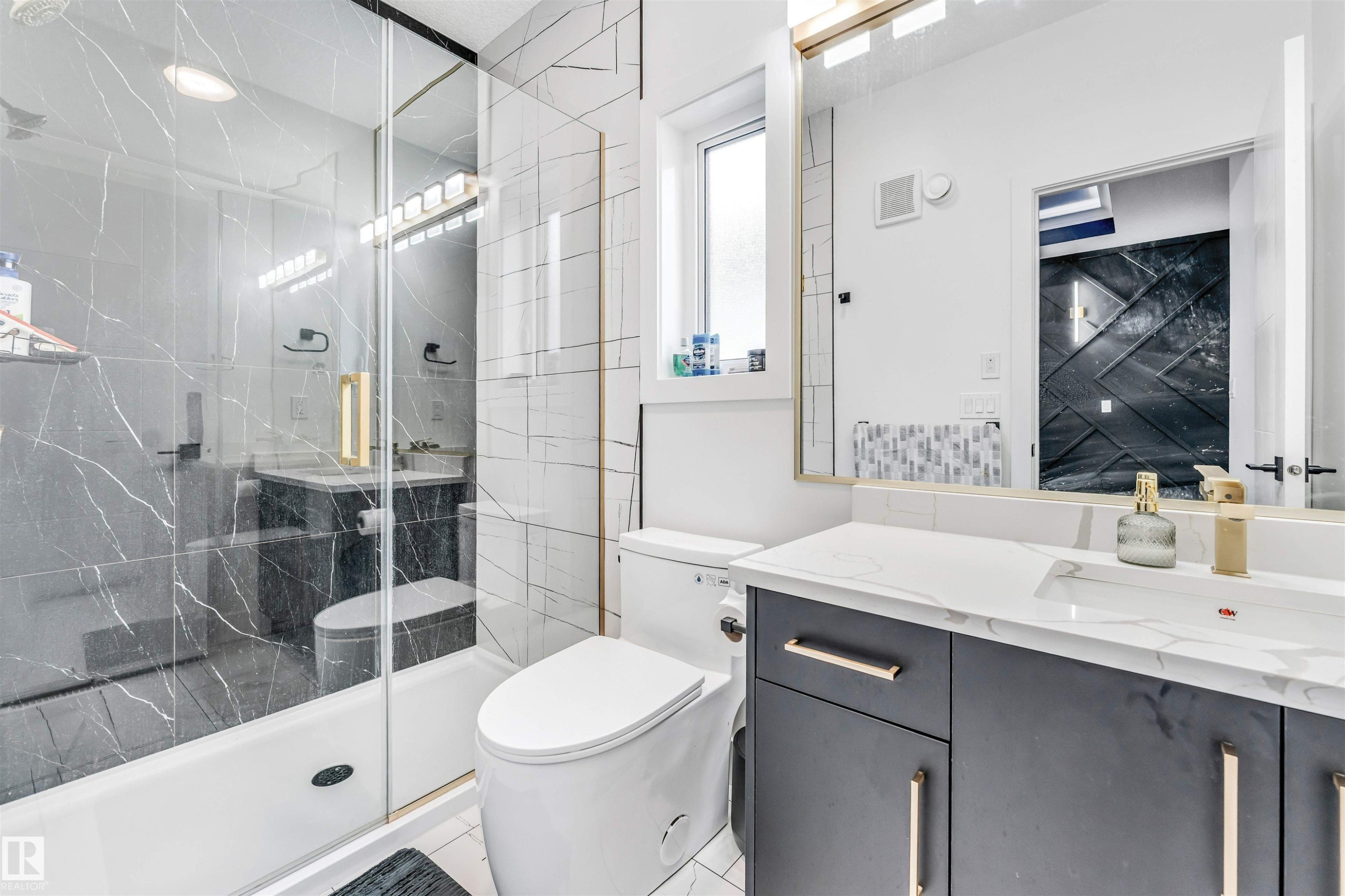 Contemporary bathroom featuring a modern vanity with a white countertop and integrated sink, gold-tone hardware, and a large wall mirror - 1827 17 Avenue, Edmonton, AB - Indoor Photo Showing Bathroom