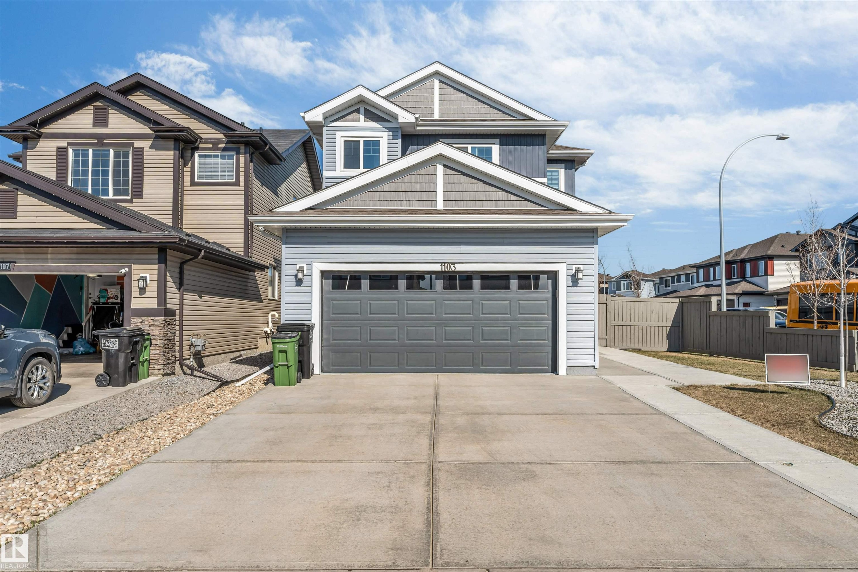 Two-story property featuring light blue siding, gray shingle accents, and a front-facing garage with a paneled door - 1103 29 Street, Edmonton, AB - Outdoor