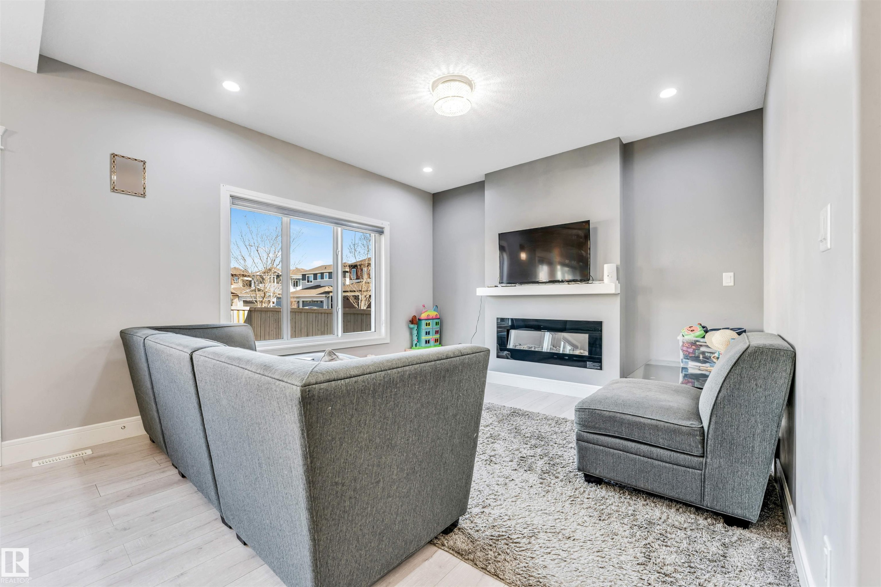 Living area featuring a contemporary electric fireplace with a white mantel, recessed lighting, and a large window - 1103 29 Street, Edmonton, AB - Indoor With Fireplace