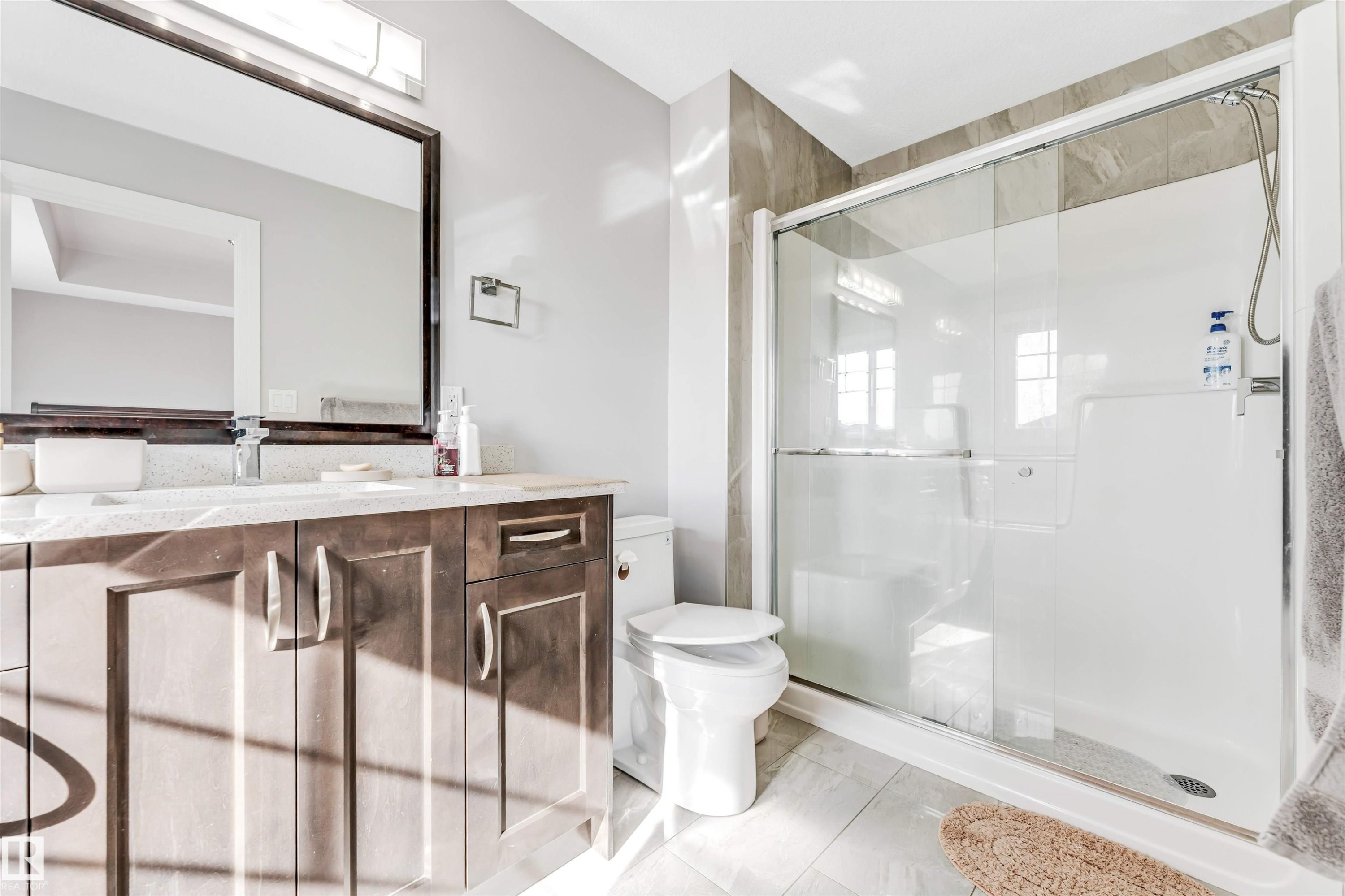 Bathroom featuring a dark wood-finish vanity with a light-colored countertop, an undermount sink, and a large framed mirror - 1103 29 Street, Edmonton, AB - Indoor Photo Showing Bathroom