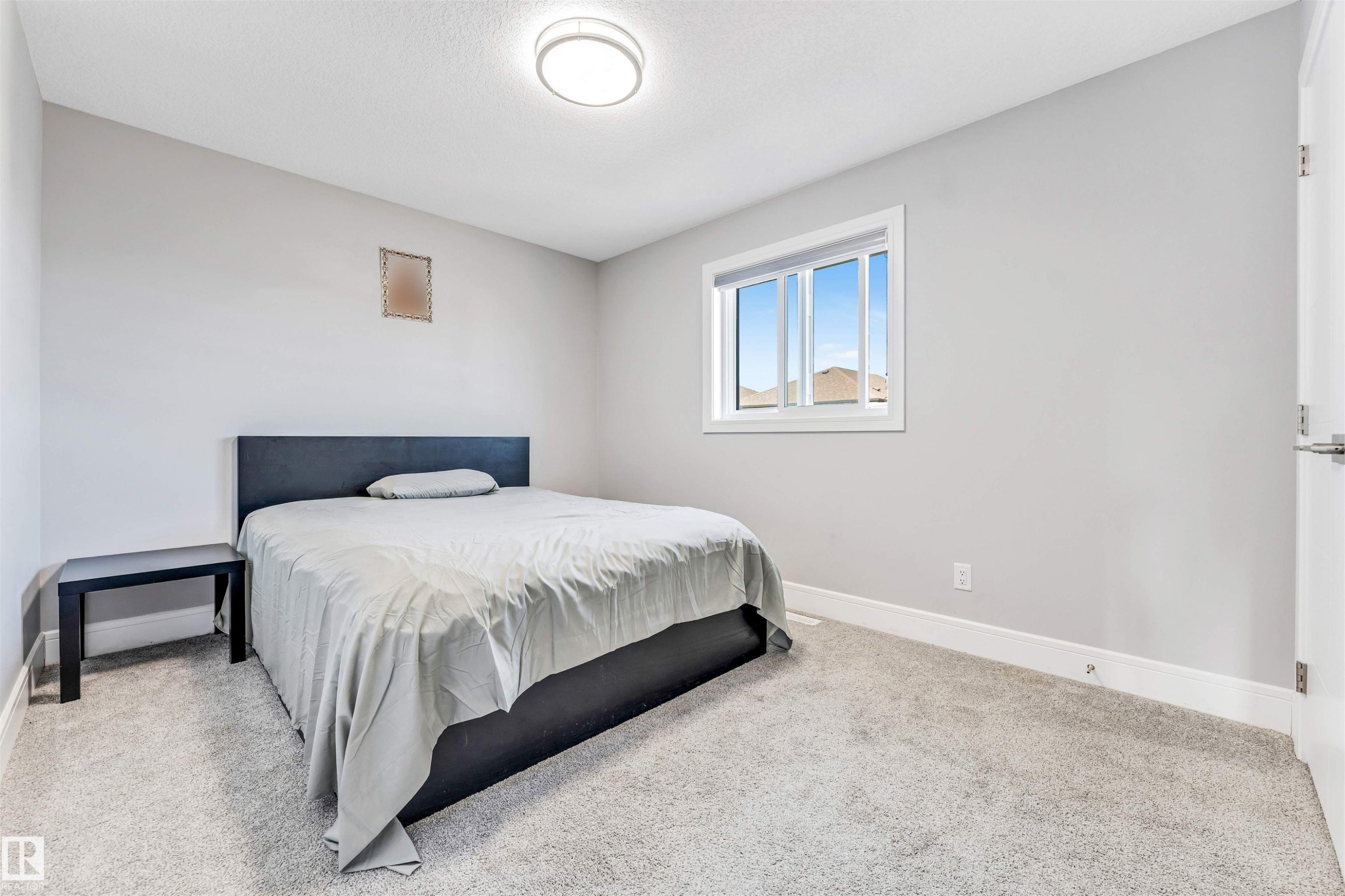 Neutral-toned room featuring a single window with white trim, light gray walls, and gray carpet flooring - 1103 29 Street, Edmonton, AB - Indoor Photo Showing Bedroom