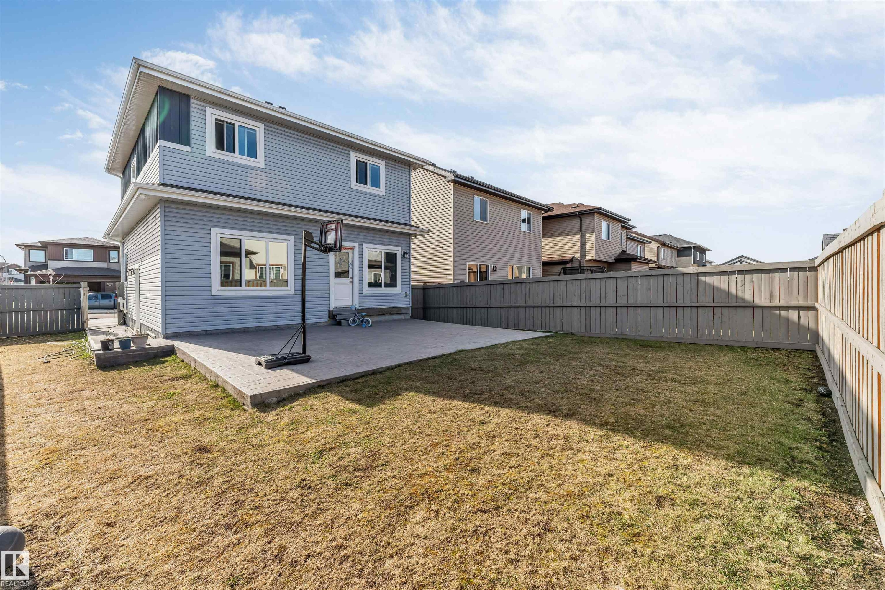 Spacious backyard featuring a concrete patio, expansive lawn area, and full perimeter wood fencing - 1103 29 Street, Edmonton, AB - Outdoor