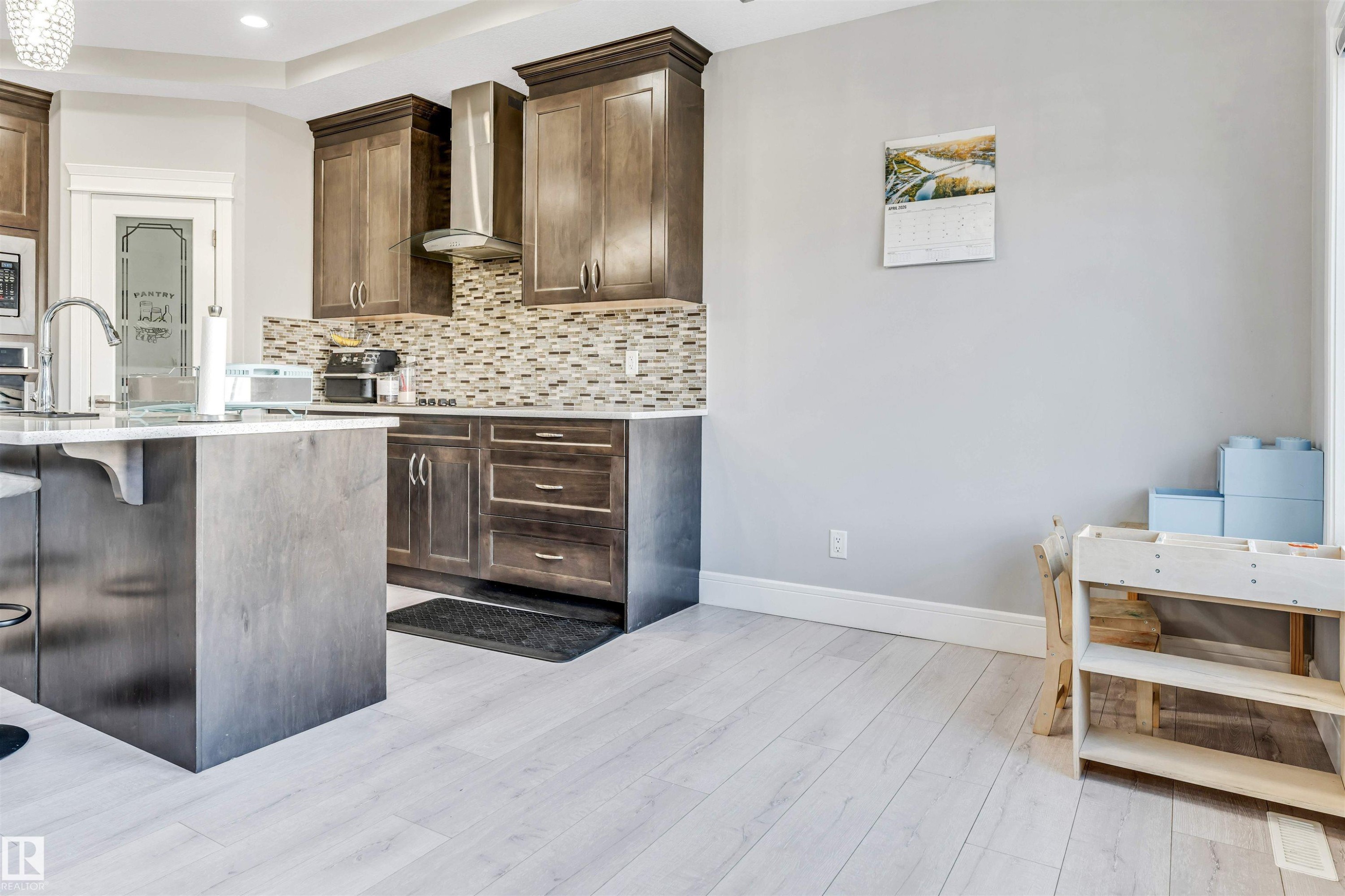 Contemporary kitchen featuring wood-finish cabinetry, a patterned tile backsplash, and light wood-finish flooring - 1103 29 Street, Edmonton, AB - Indoor Photo Showing Kitchen With Upgraded Kitchen