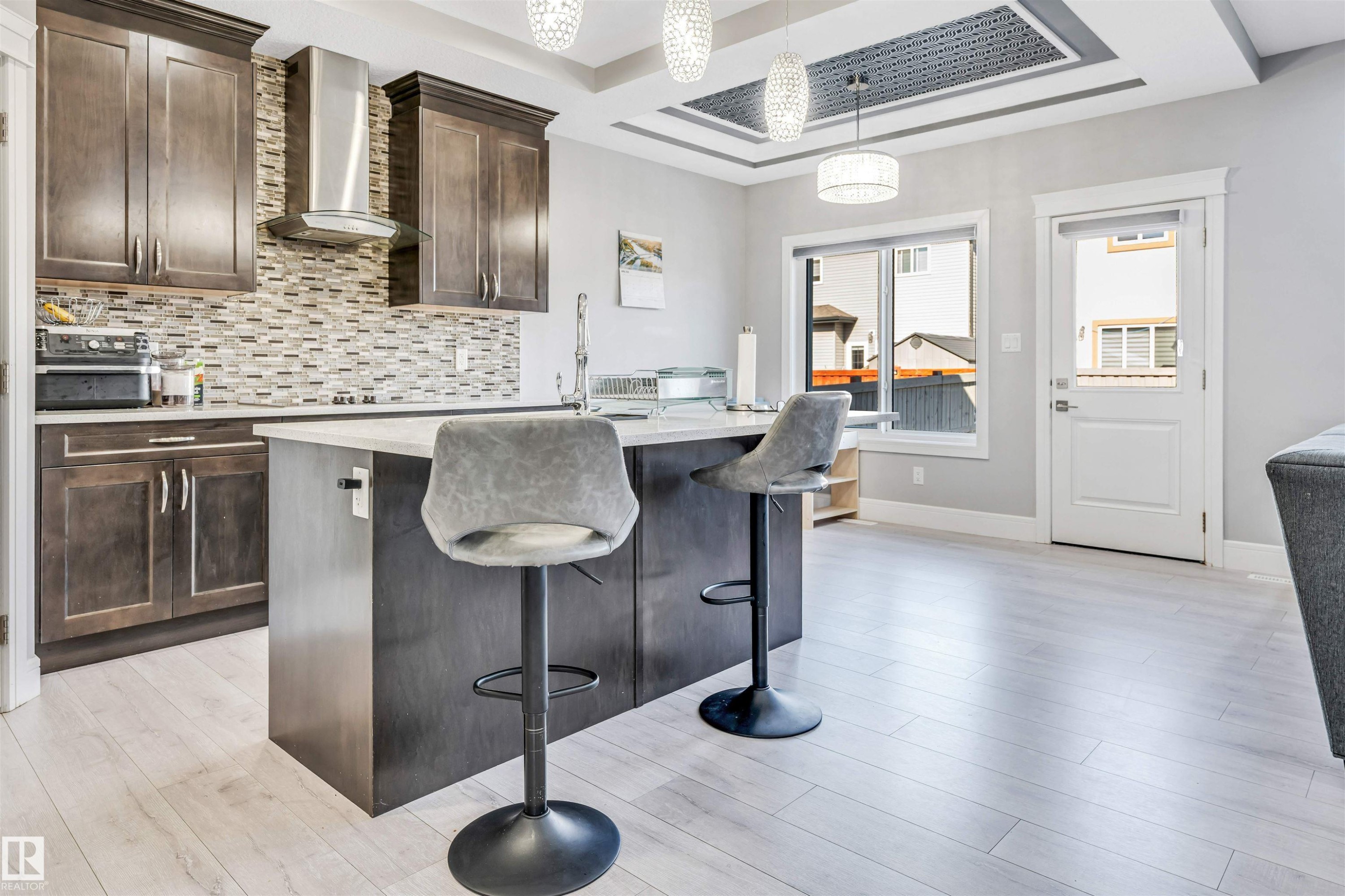 Modern kitchen featuring dark wood cabinetry, light countertops, and a mosaic tile backsplash - 1103 29 Street, Edmonton, AB - Indoor