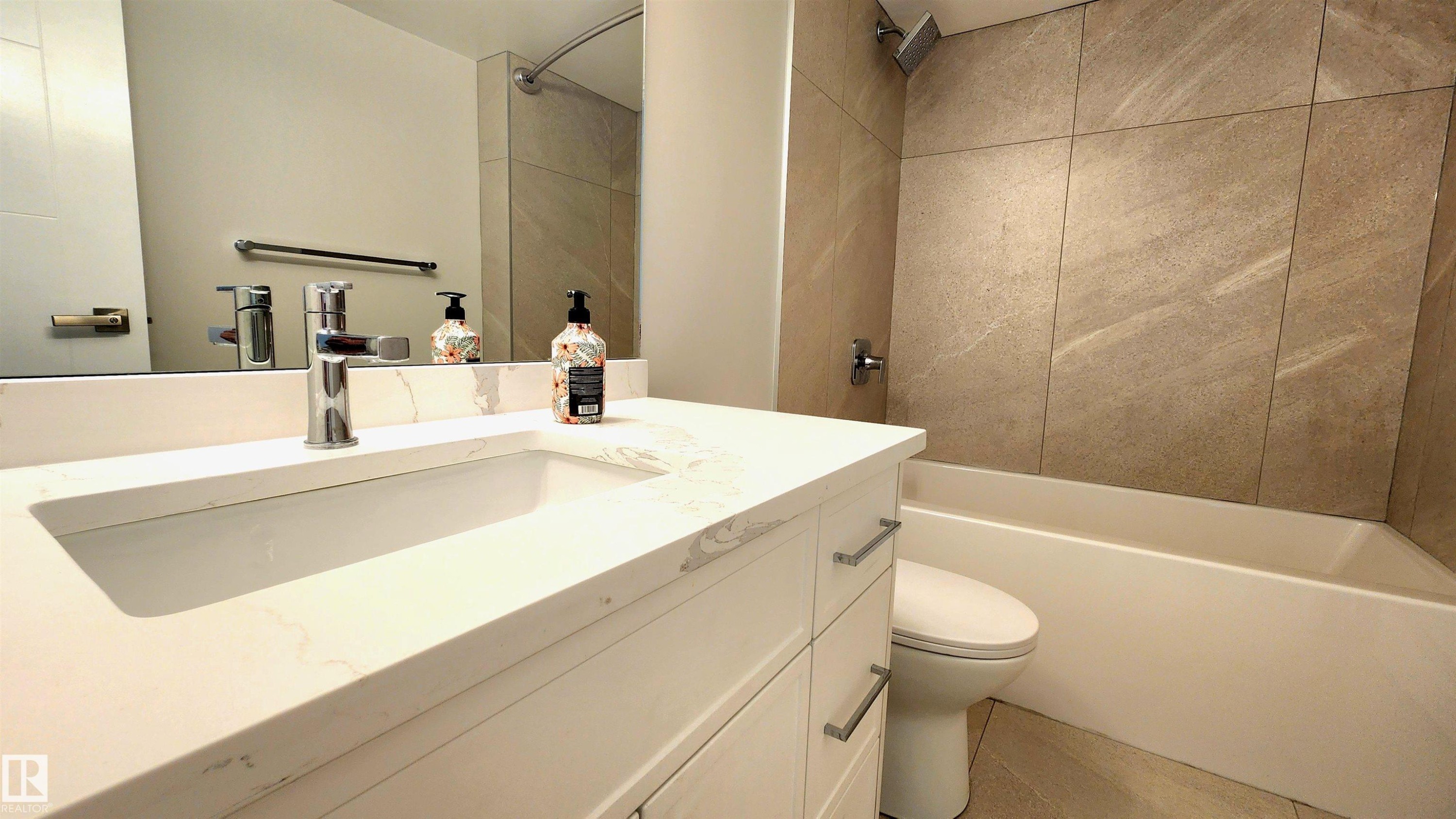 White vanity with integrated rectangular sink and polished chrome faucet - 603 9028 Jasper Avenue, Edmonton, AB - Indoor Photo Showing Bathroom
