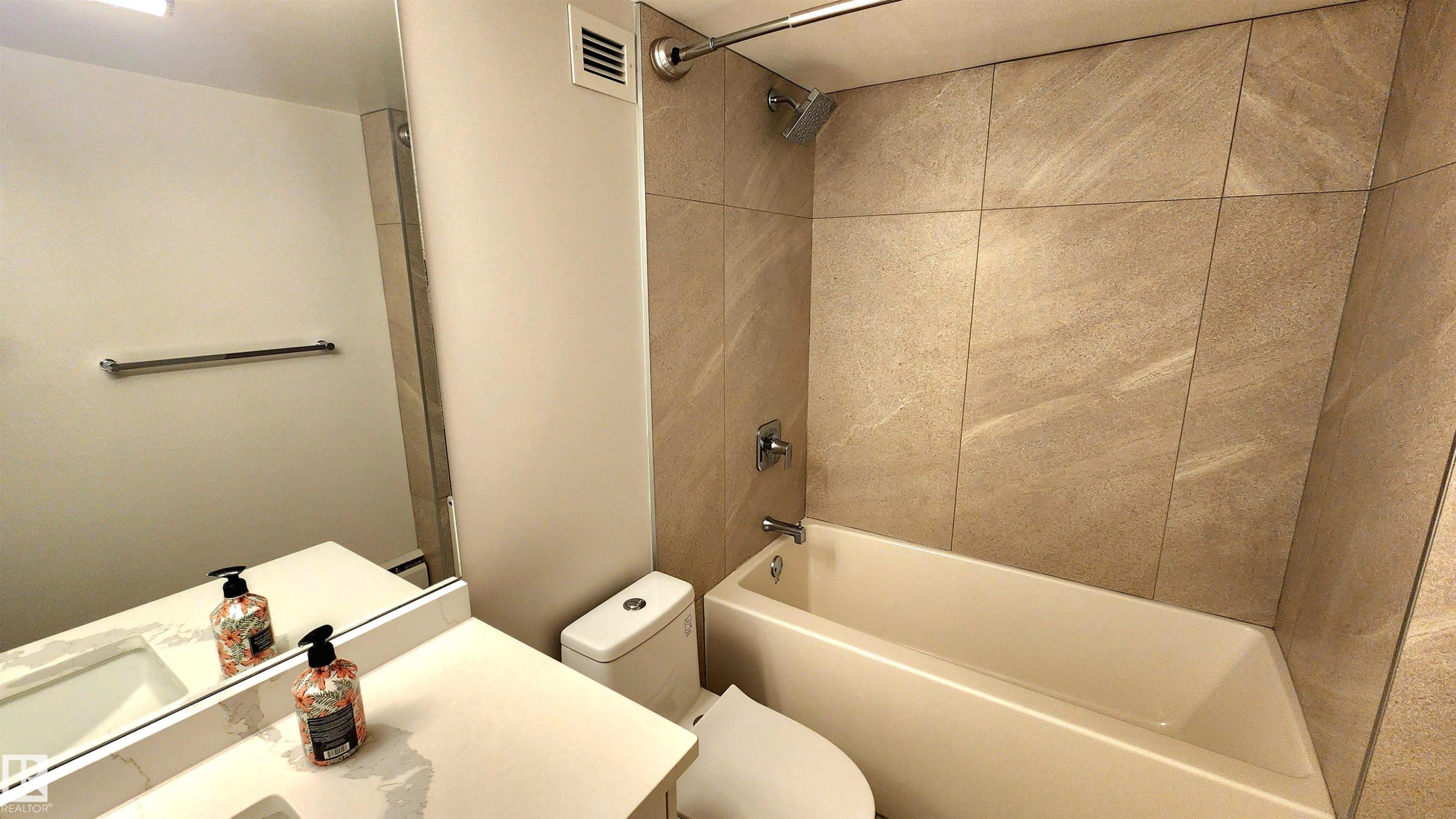 Bathroom featuring a full vanity with an integrated sink, a rectangular mirror, a chrome towel bar, and a tub-shower combination with floor-to-ceiling tile surround - 603 9028 Jasper Avenue, Edmonton, AB - Indoor Photo Showing Bathroom