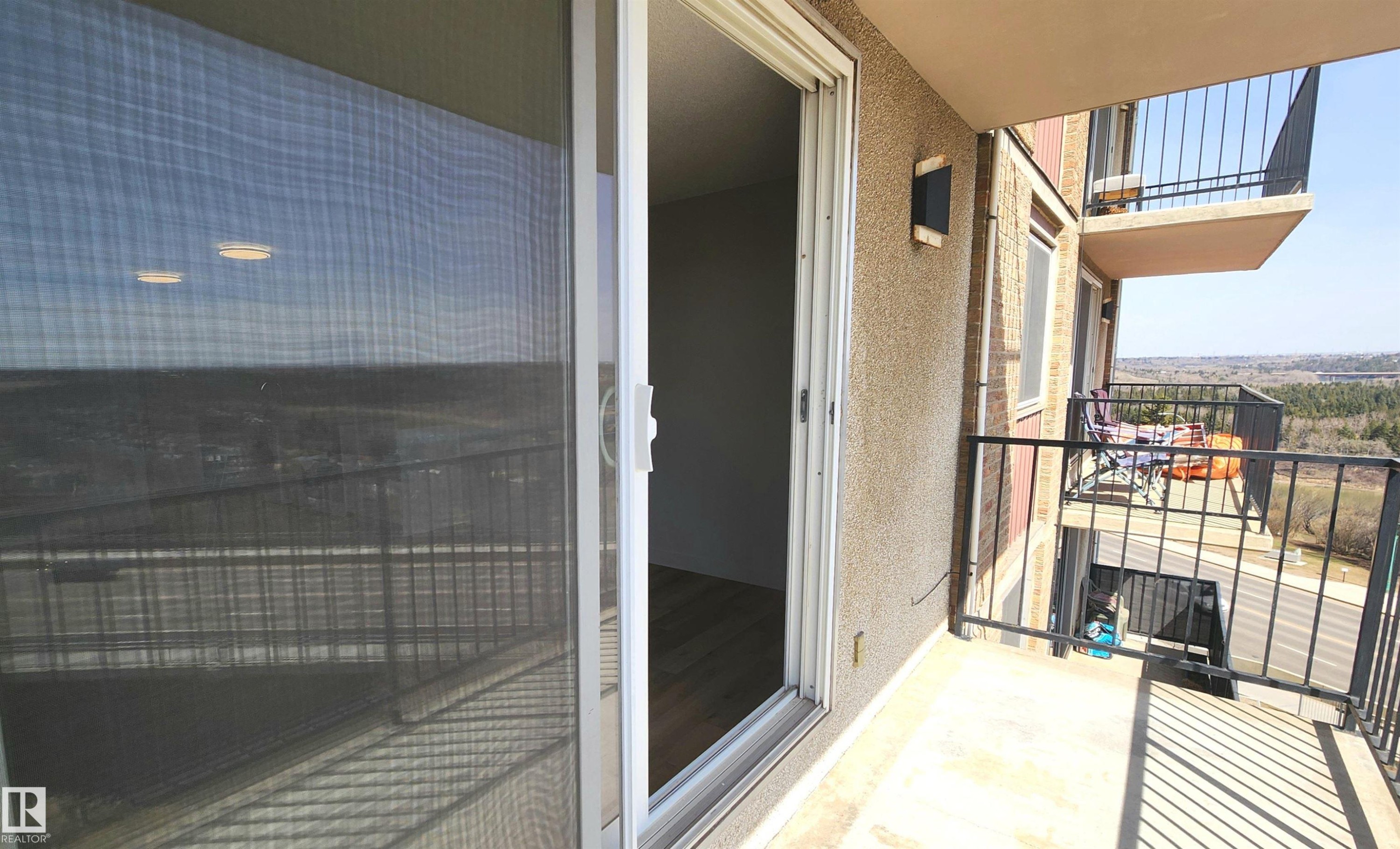 Private balcony with concrete flooring and black metal railings, featuring an exterior wall sconce - 603 9028 Jasper Avenue, Edmonton, AB - Outdoor With Exterior