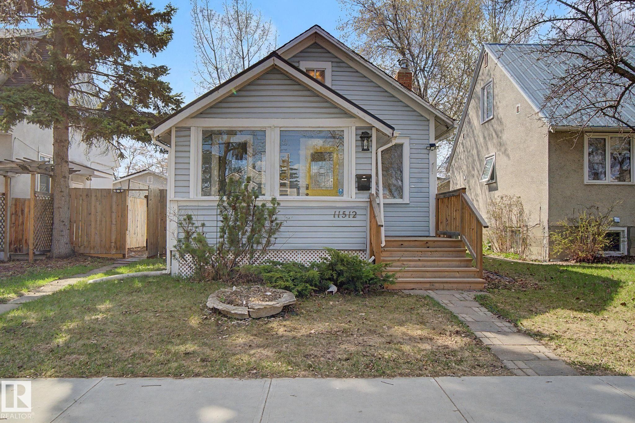 Light blue siding exterior featuring a prominent front porch with wood stairs and railing - 11512 122 St, Edmonton, AB - Outdoor With Facade
