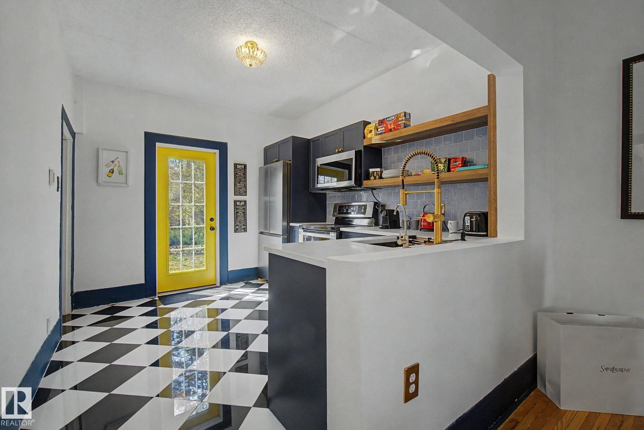 Kitchen featuring checkered tile flooring, white countertops, dark cabinetry, and a gold-finish faucet - 11512 122 St, Edmonton, AB - Indoor Photo Showing Kitchen