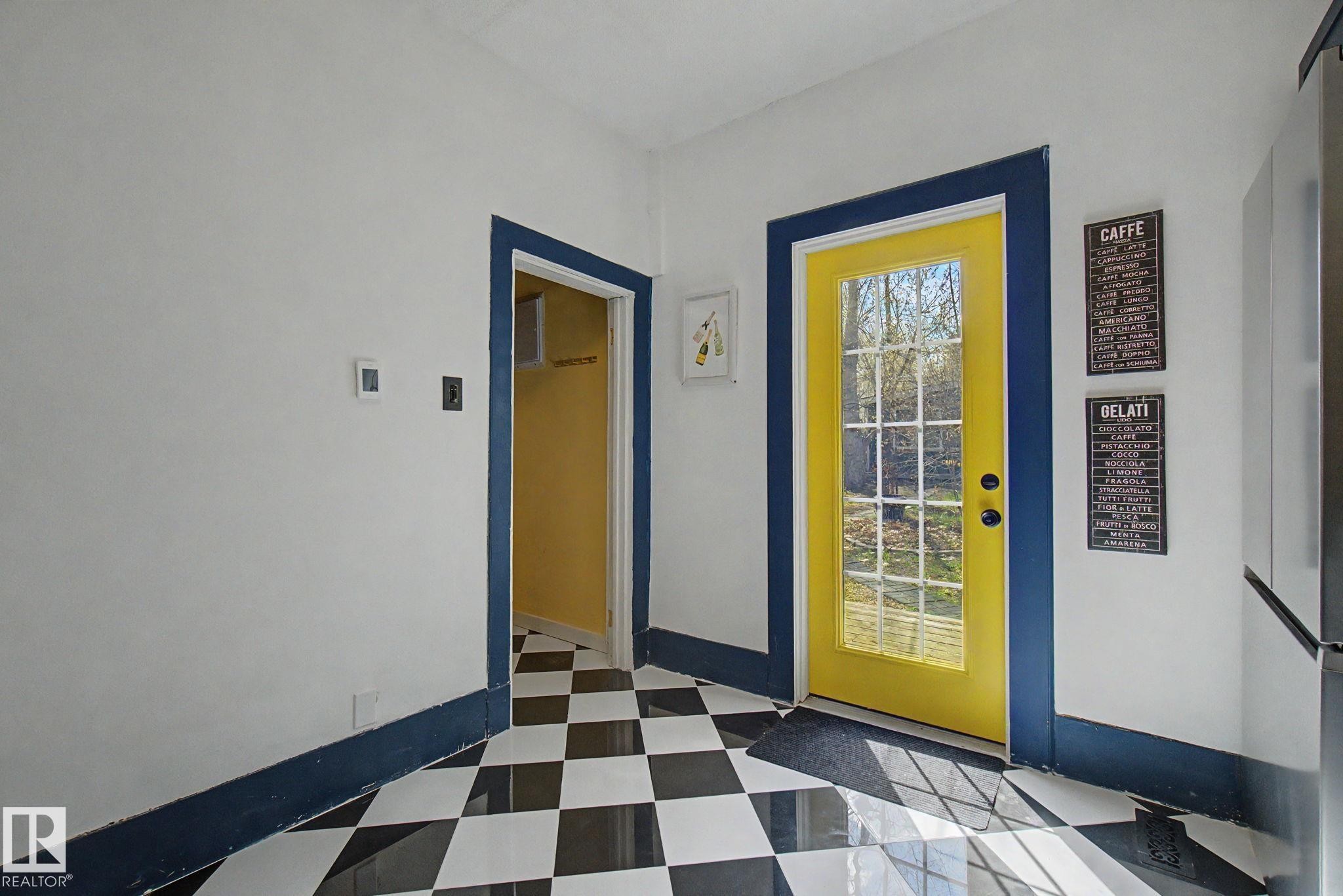 Black and white checkerboard flooring with a bright yellow multi-pane door - 11512 122 St, Edmonton, AB - Indoor Photo Showing Other Room