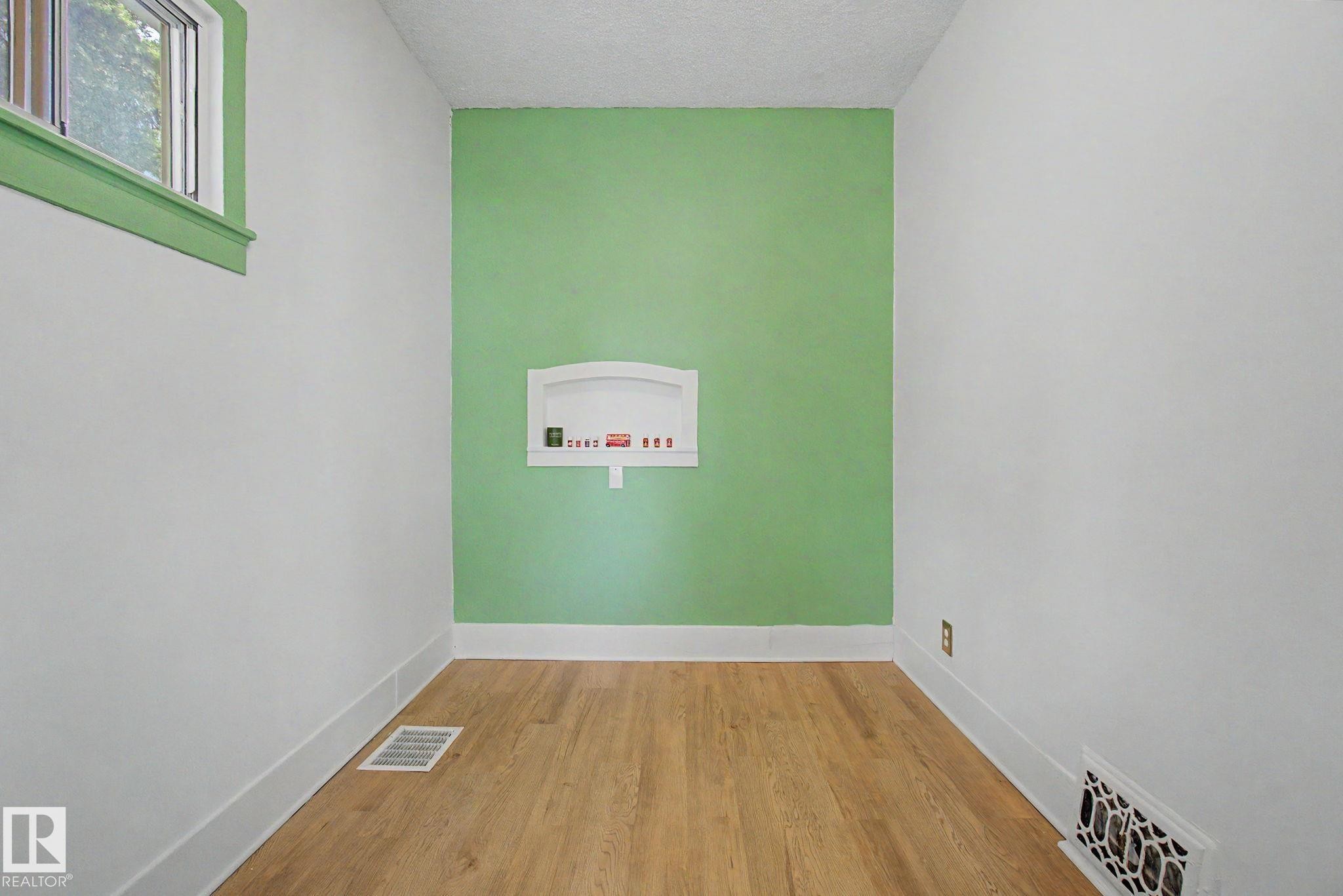 Light wood-finish flooring complemented by white baseboards and walls - 11512 122 St, Edmonton, AB - Indoor Photo Showing Other Room