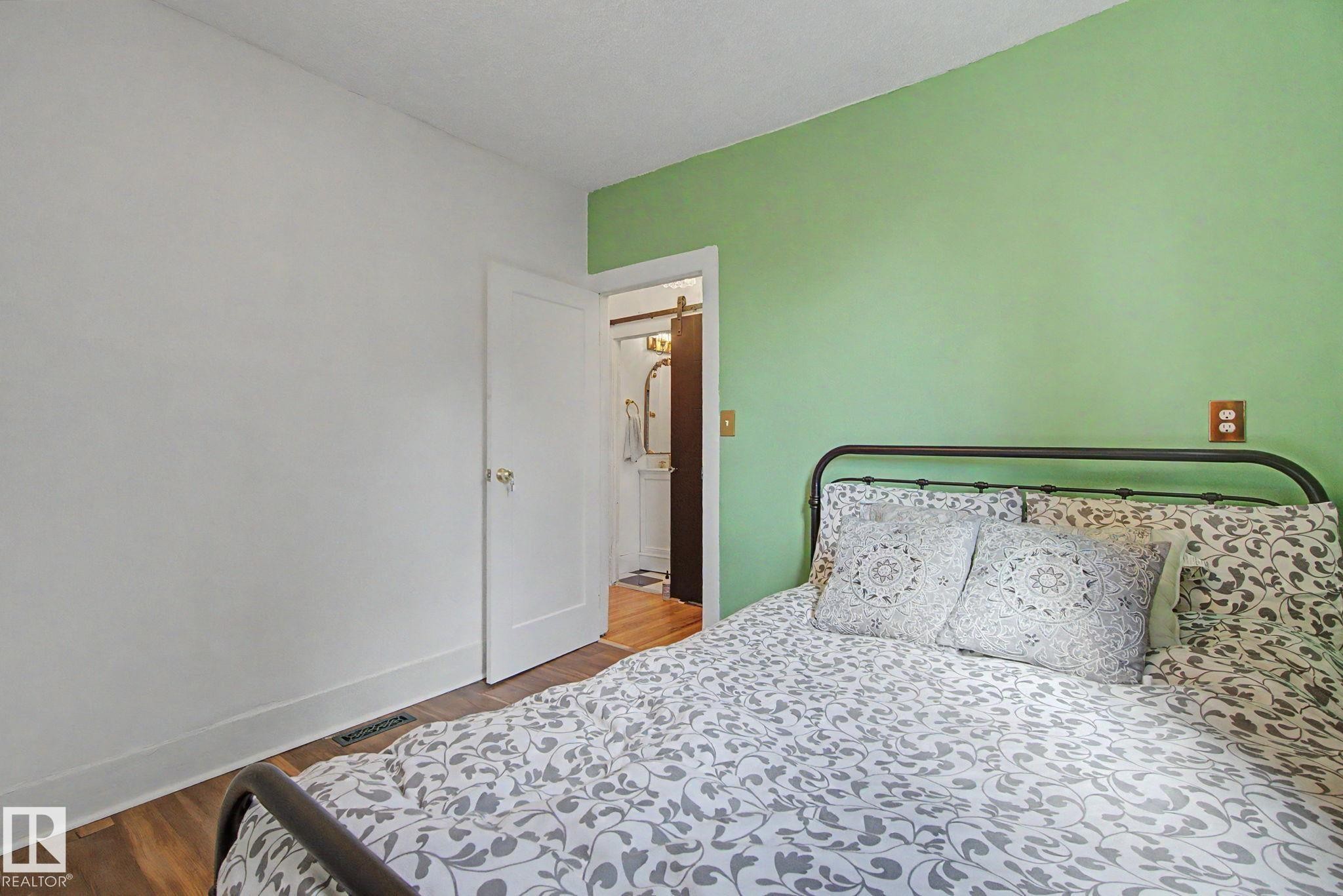 Room featuring wood-finish flooring and a white door with brass hardware - 11512 122 St, Edmonton, AB - Indoor Photo Showing Bedroom