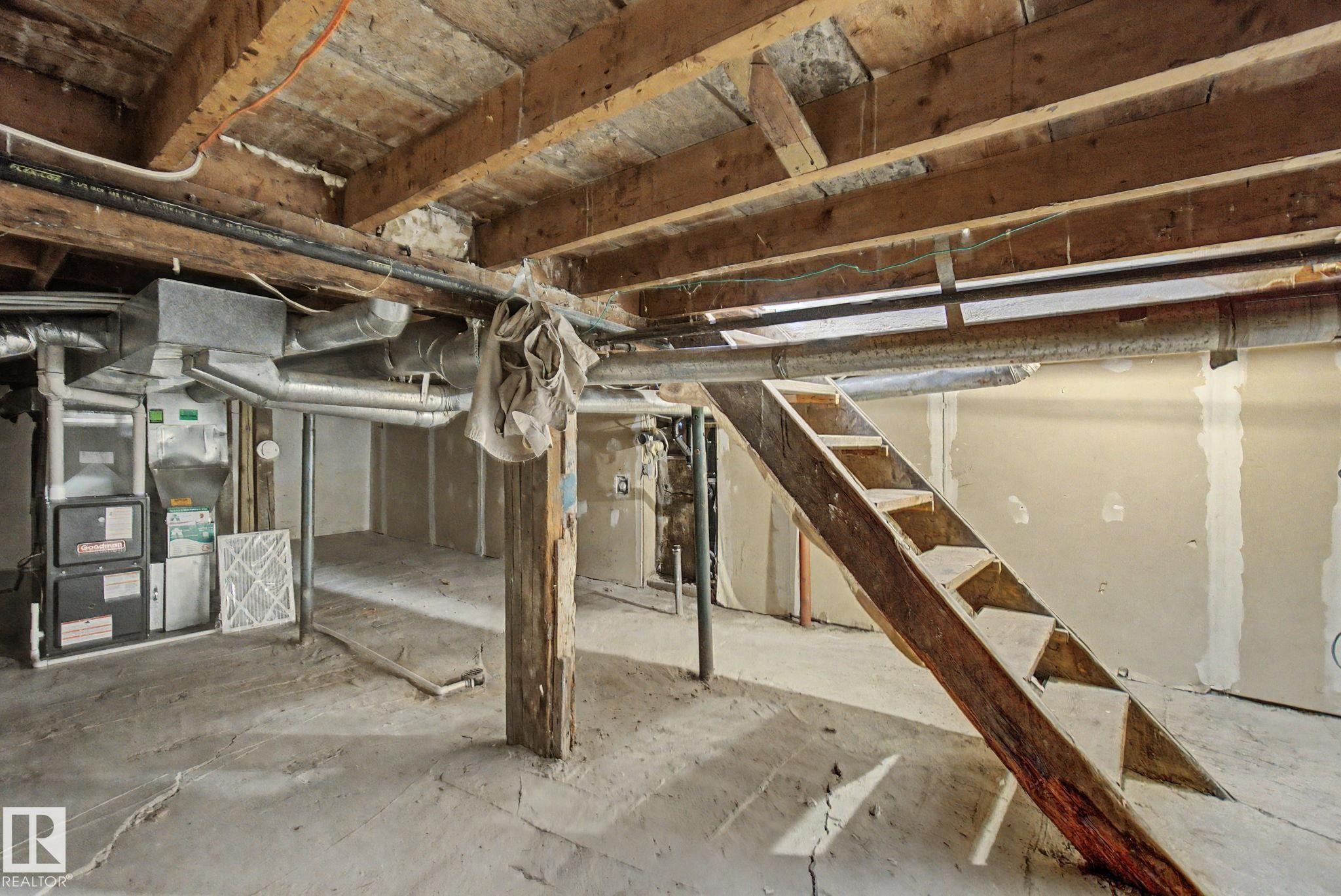 Unfinished basement featuring exposed wood joists, concrete flooring, and an existing furnace unit - 11512 122 St, Edmonton, AB - Indoor Photo Showing Basement