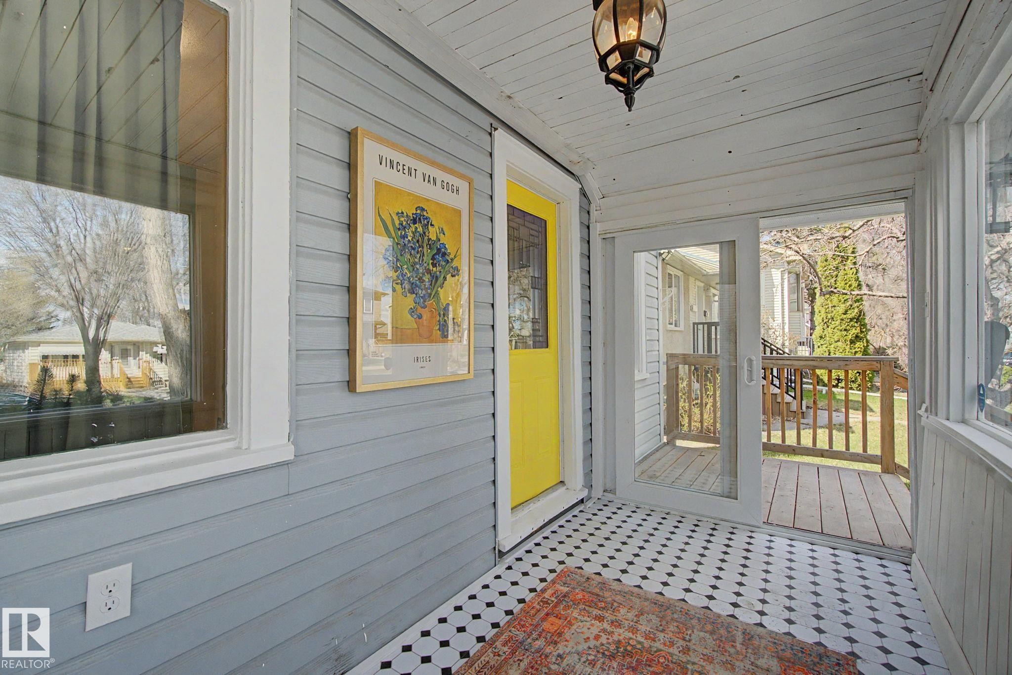 Enclosed porch featuring a yellow entry door, black and white hexagon tile flooring, and white paneled walls and ceiling - 11512 122 St, Edmonton, AB - Outdoor With Exterior