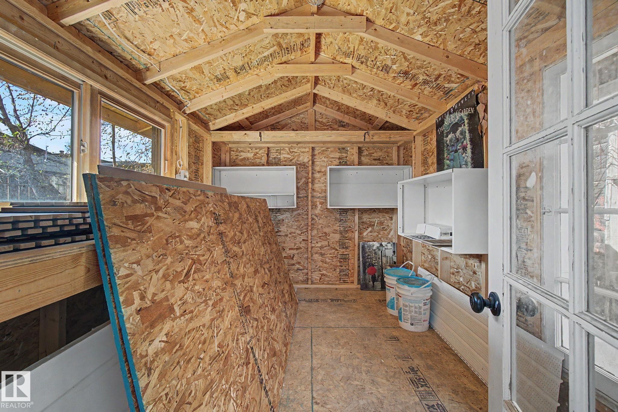 Unfinished interior space featuring exposed wood framing, wood-finish flooring, and two windows providing natural illumination - 11512 122 St, Edmonton, AB - Indoor