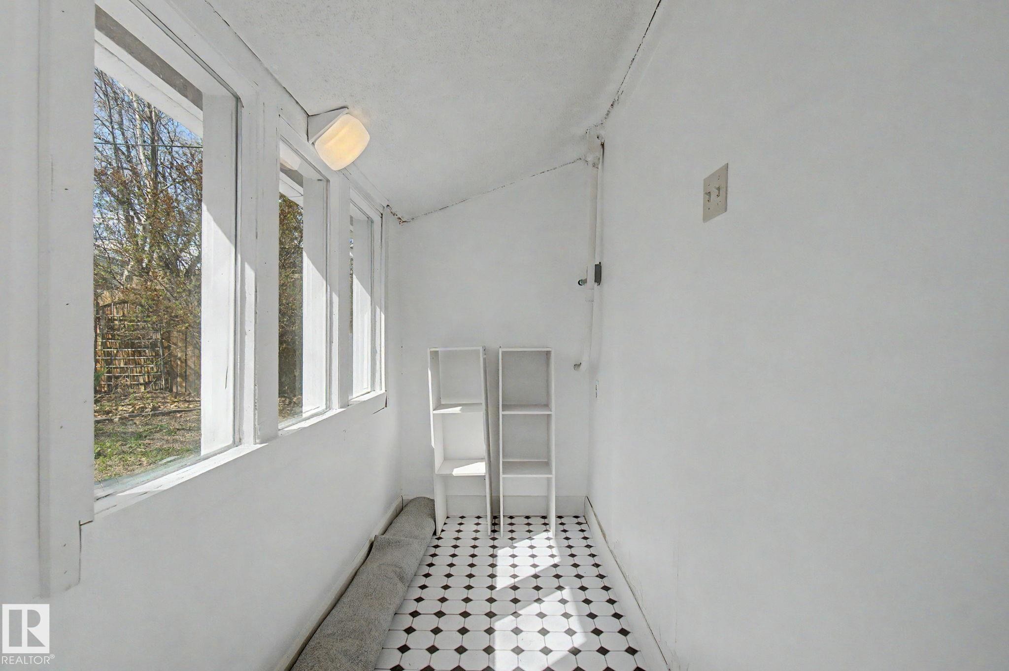 Sunroom featuring a black and white diamond pattern floor tile, a full wall of vertical windows, and a flush-mount ceiling light fixture - 11512 122 St, Edmonton, AB - Indoor Photo Showing Other Room