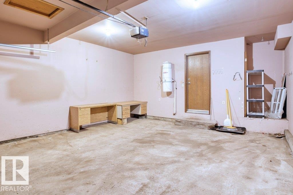 The property features a garage with a concrete floor, painted walls, and a visible garage door opener mechanism - 17313 60 Avenue, Edmonton, AB - Indoor
