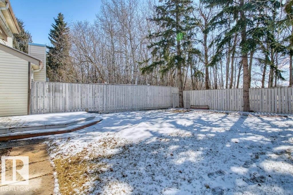 The property features a fenced yard with mature trees and a deck - 17313 60 Avenue, Edmonton, AB - Outdoor