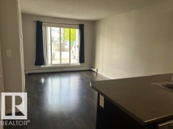 Spacious interior featuring dark wood-finish flooring, light-toned walls, and a sliding glass door providing natural light -