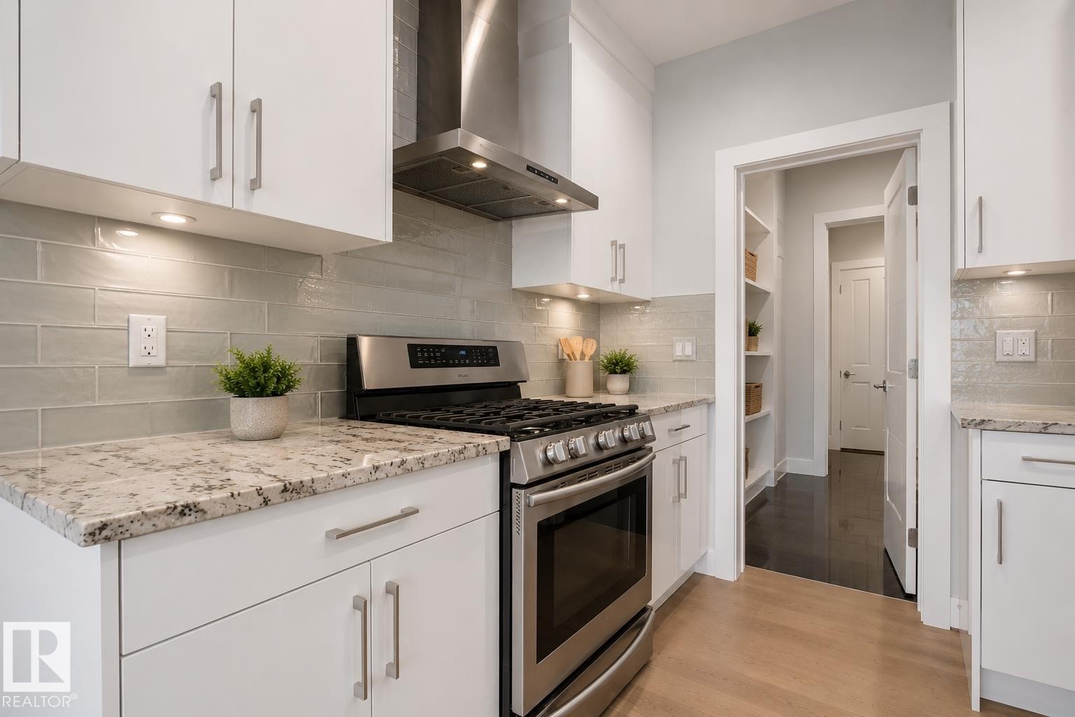 Modern kitchen featuring white cabinetry, light-toned granite countertops, stainless steel appliances, a subway tile backsplash, and light wood-finish flooring. Virtually Staged. - 635 42 Street, Edmonton, AB - Indoor Photo Showing Kitchen With Upgraded Kitchen