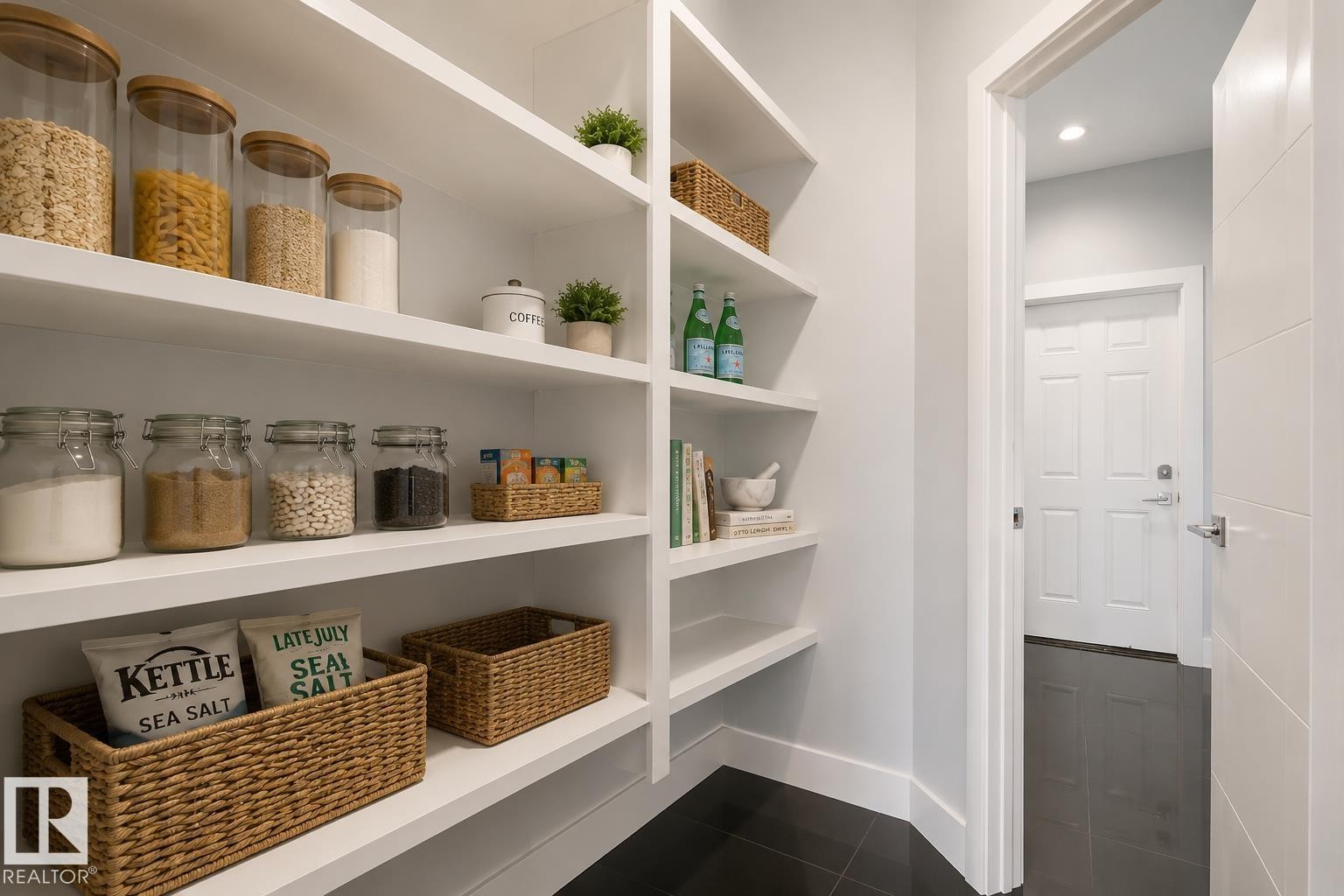 Built-in open shelving providing ample storage, dark tile flooring, and a white interior door with contemporary hardware. Virtually Staged. - 635 42 Street, Edmonton, AB - Indoor With Storage